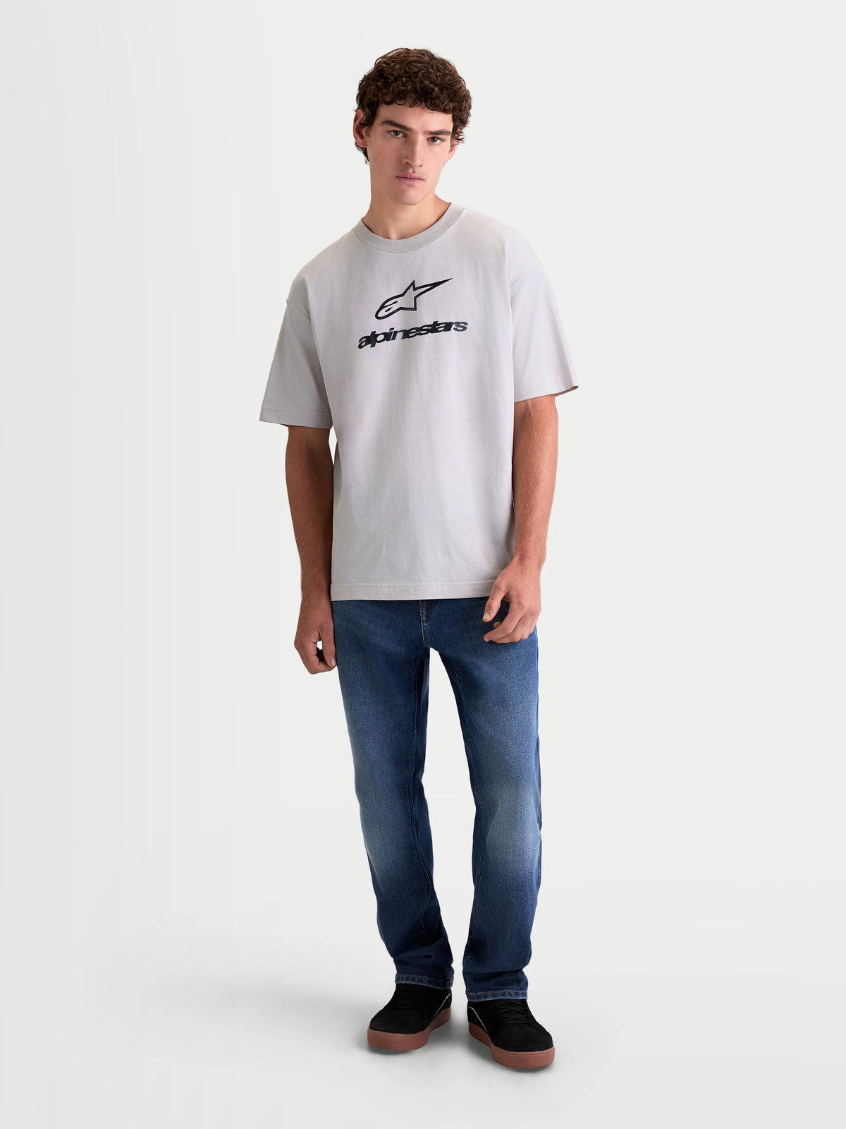 Alpinestars Prelude Oversized CSF t-shirt på modell, cementgrå kortärmad t-shirt med svart Astars-logotyp på bröstet, oversized passform i mjuk bomullsblandning för en avslappnad livsstil.