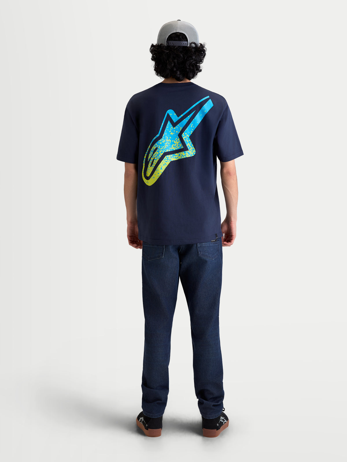 Alpinestars Meteor CSF t-shirt, marinblå kortärmad sportswear-tröja, bakifrån på modell, stor gul och cyan MX-inspirerad gradient Astars-logotyp på ryggen, mjuk bomulls- och polyesterblandning för vardagskomfort.