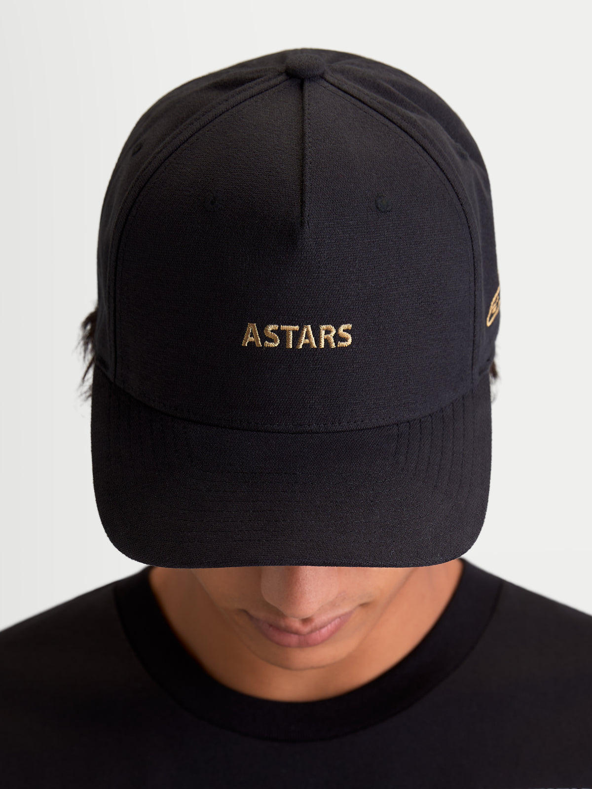 Alpinestars County Canvas hatt, svart sportswear-keps med guld ASTARS-logobroderi, böjd skärm och strukturerad krona, unisex motorsportinspirerad keps för vardagsbruk, peachad oxfordväv, framifrån på modell