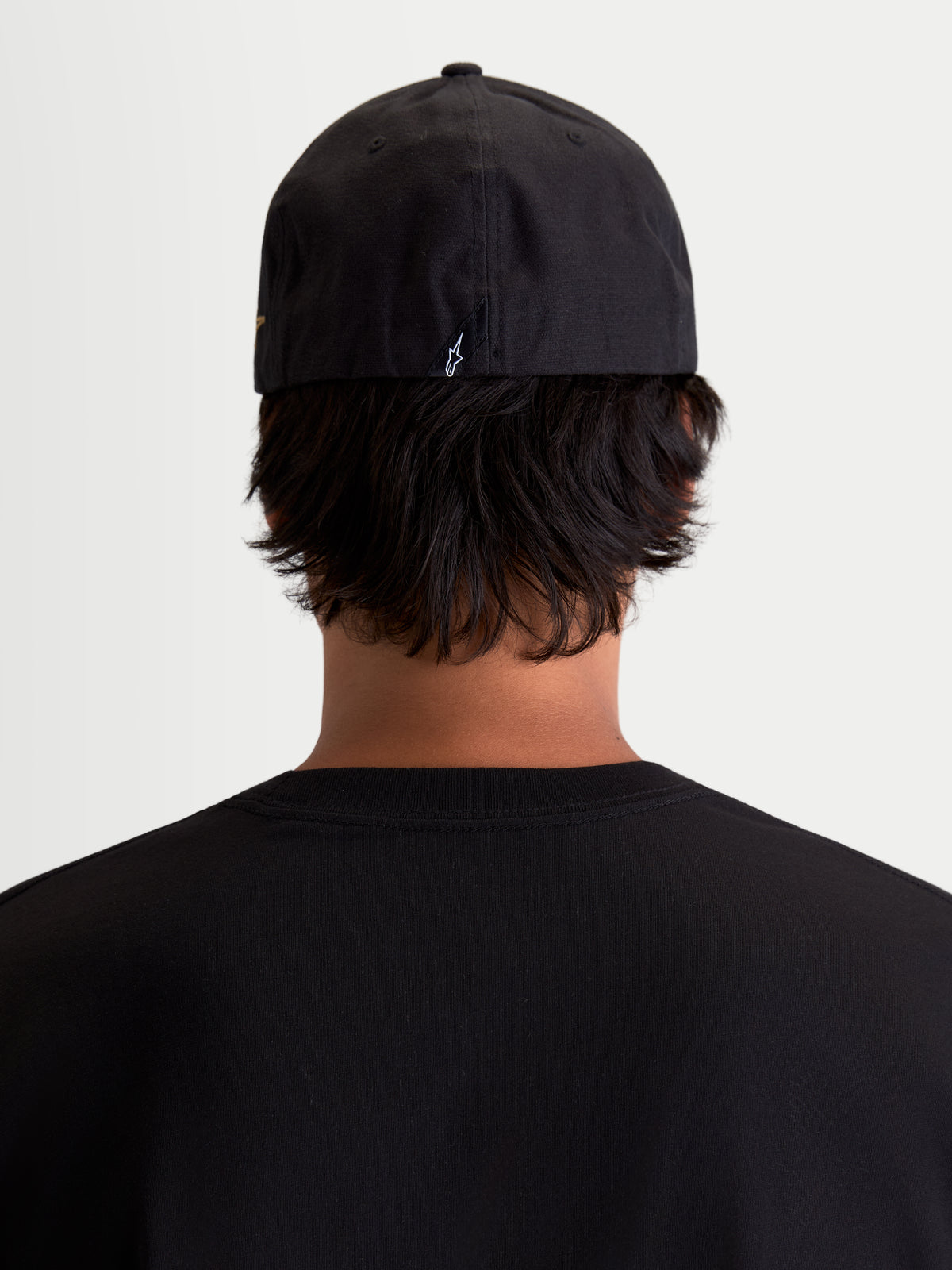Alpinestars County Canvas hatt, svart sportswear-keps sedd bakifrån på modell, flexibel passform med liten broderad Astars-logotyp baktill, mjukt peachad oxfordväv för vardagskomfort.