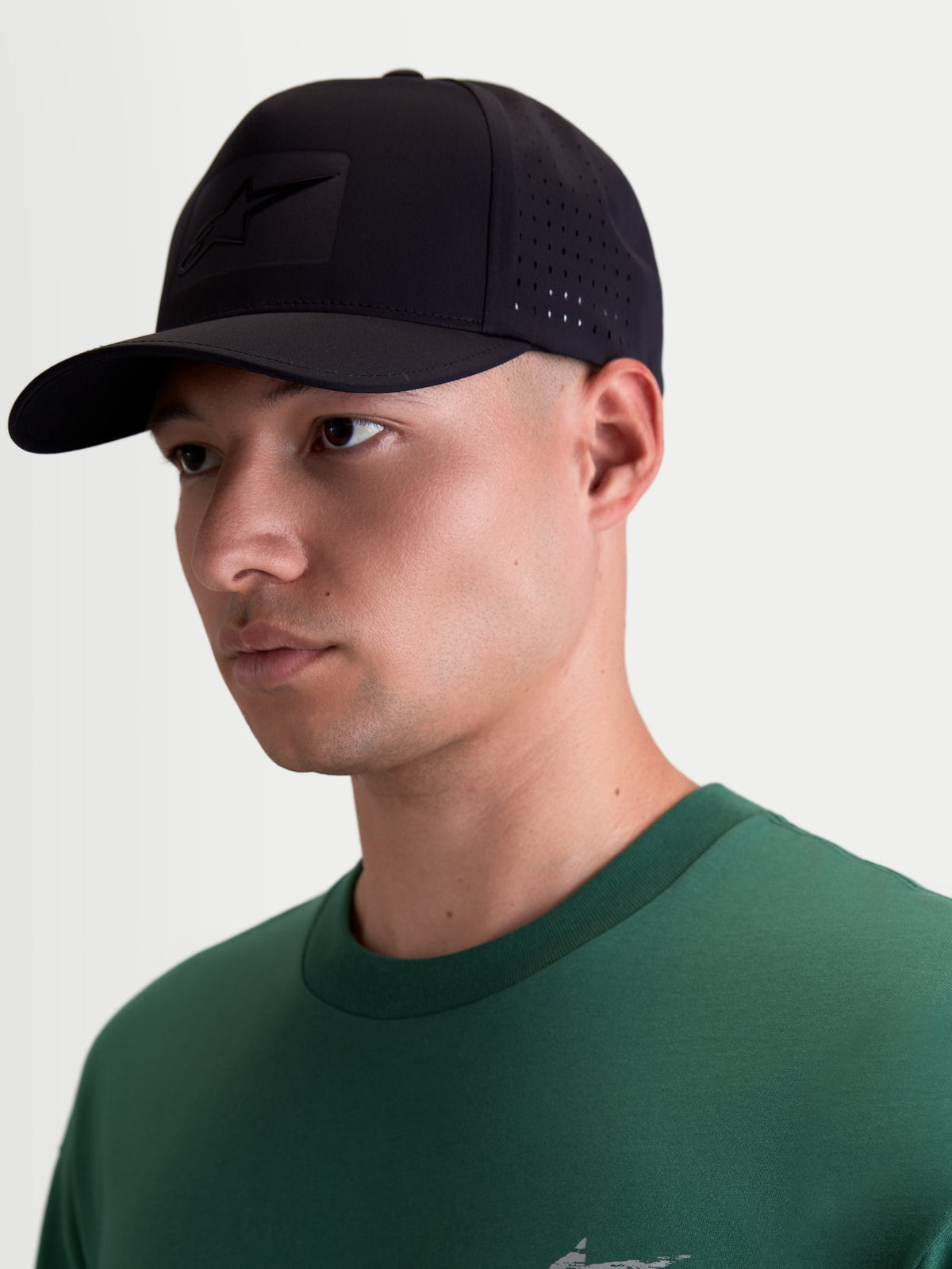 Alpinestars Algo Perf Adjustable keps, svart motorsportinspirerad keps i tekniskt tyg med sidoperforeringar för ventilation, böjd skärm och en tonal sonic-weldad Astars-logotyp.