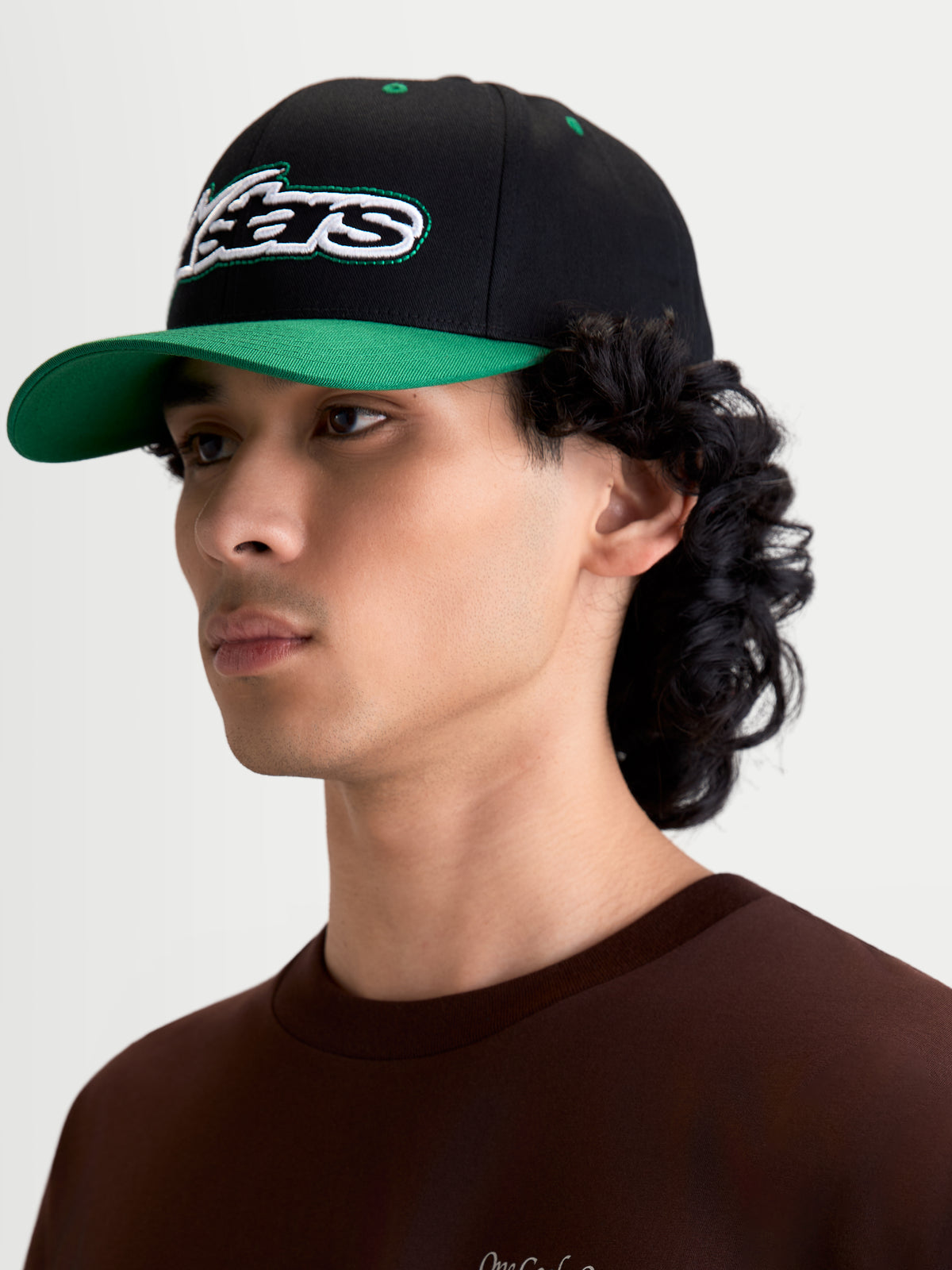Alpinestars Retro Snapback keps, svart och grön sportkeps för vardagsbruk på manlig modell, böjd skärm, strukturerad krona och broderad Astars-logotyp med grön sticksöm, bomullstwill