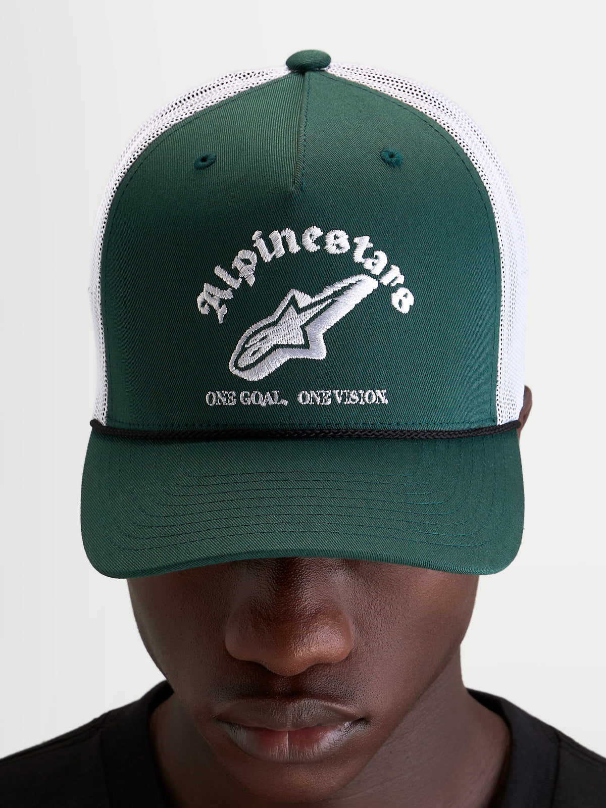 Alpinestars Baron Trucker keps, grön och vit trucker-keps för vardagsbruk med böjd skärm, ventilerande meshbaksida och broderad Alpinestars-logotyp, bärs av en modell