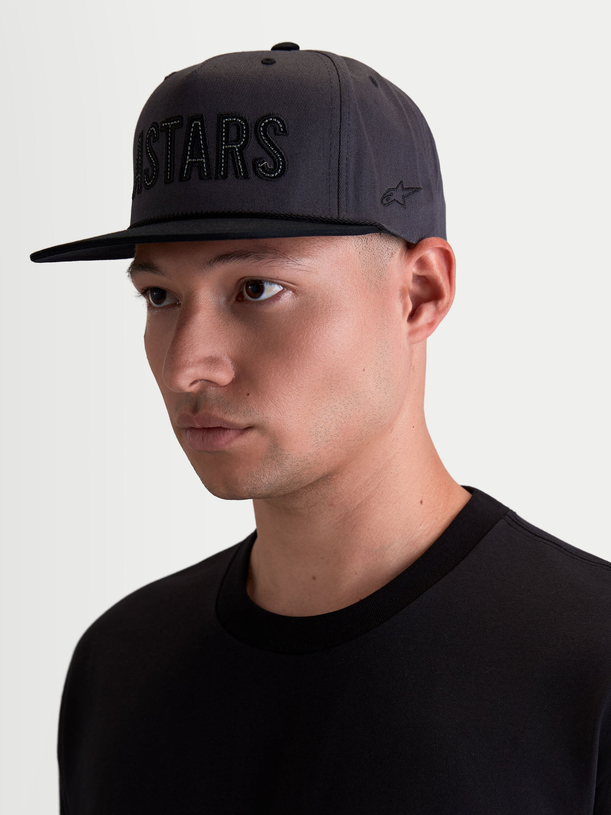 Alpinestars Stadium Snapback keps, motorsport-inspirerad snapback-keps för herr, mörkgrå och svart, strukturerad krona med platt skärm, Astars-logotypapplikation fram och sidobroderi, slitstark bomullstwill, modellvy.