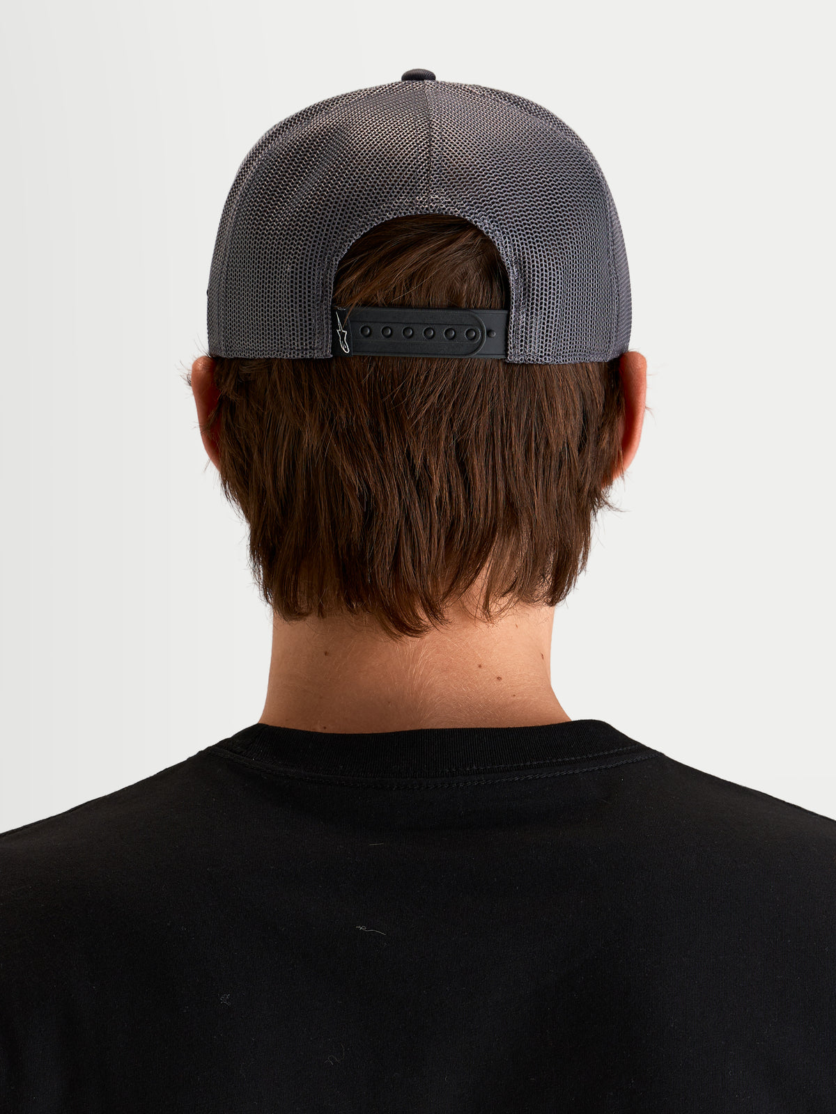 Alpinestars Ten keps, mörkgrå sportswear-truckerkeps med meshpaneler bak, vy bakifrån på modell som visar justerbar snapback-stängning och bakre märkningsdetalj