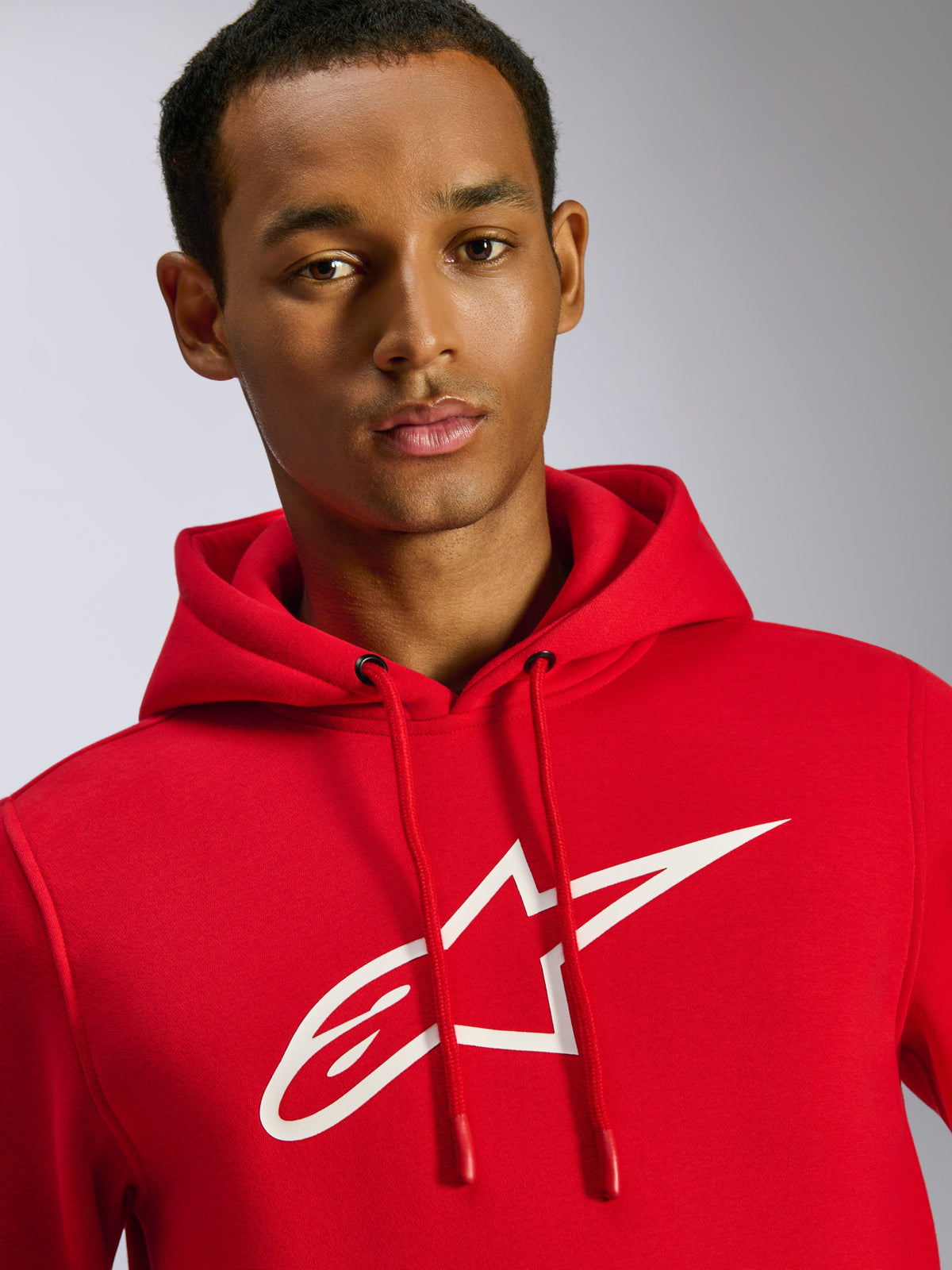 Alpinestars Ageless V3 Hoodie, Red, featuring a large white Alpinestars logo on the chest, drawstring hood with dipped tips, casual motorsport-inspired streetwear, worn by male model