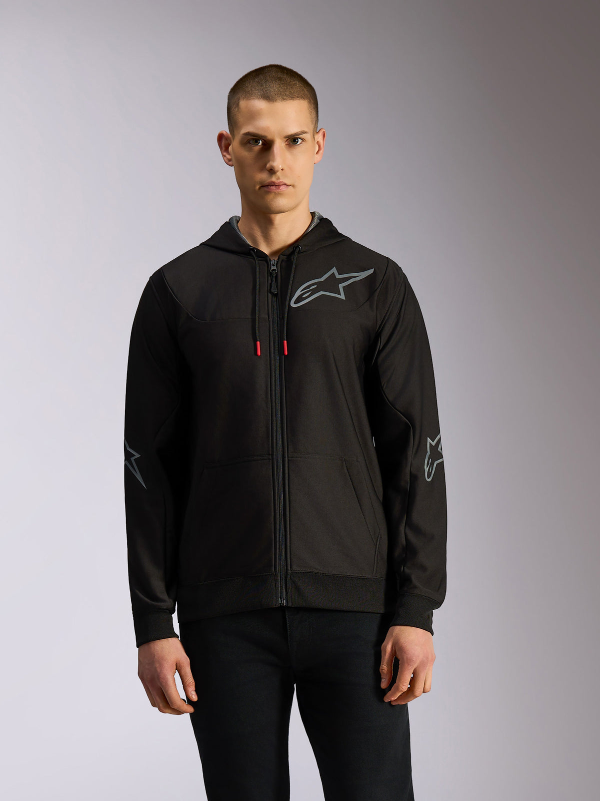 Alpinestars Sessions V3 Hoodie, huvtröja i polyfleece med dragkedja i svart och grått, grå stjärnlogotyper på bröstet och armbågarna, tekniska dragskor med röda ändar, casual motorsport-streetwear-stil