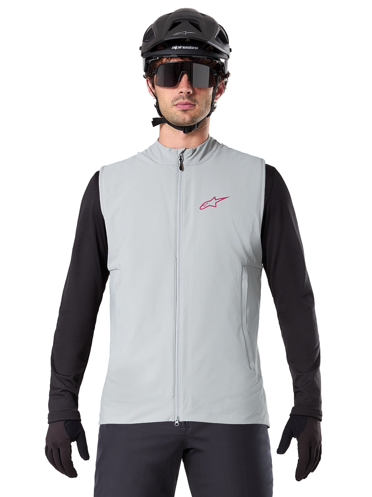 Alpinestars A-Dura Termisk Väst, cykelväst, titaniumgrå, bärs med en svart långärmad tröja och svart cykelhjälm, röd Alpinestars-stjärnlogotyp på bröstet, lätt och isolerad för mountainbikecykling