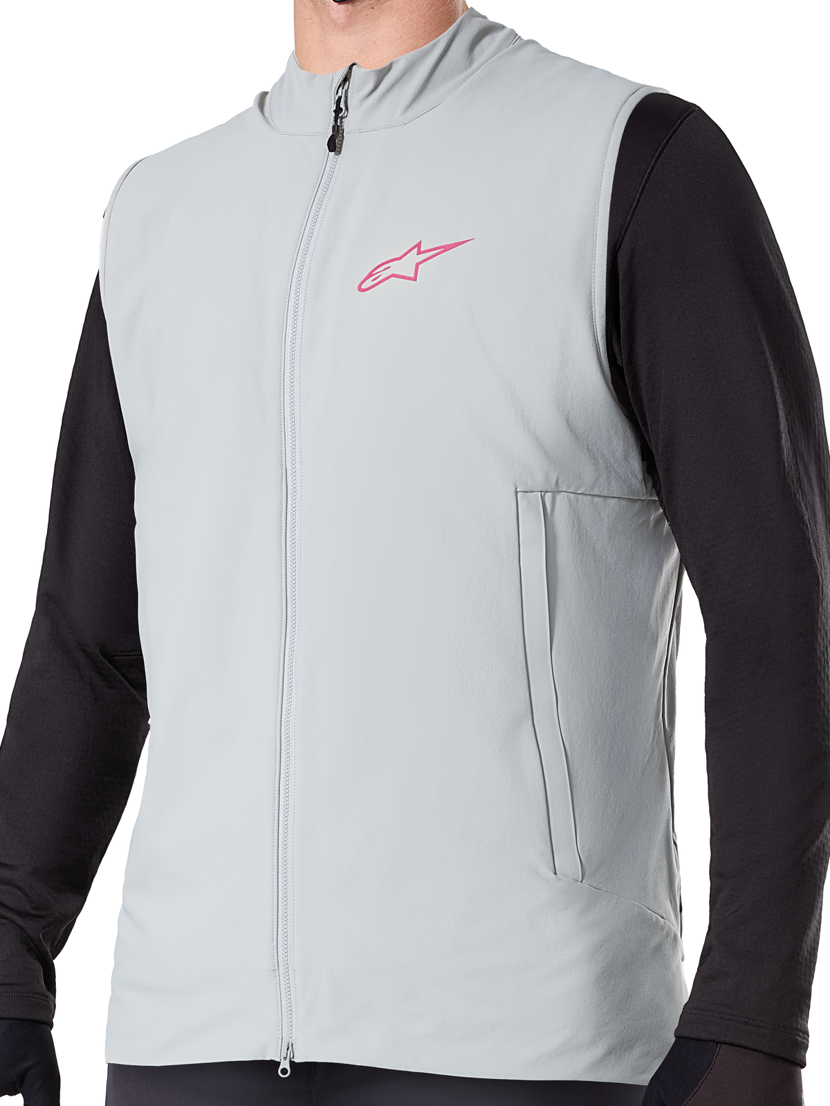 Alpinestars A-Dura Thermal Vest, titaniumgrå isolerad cykelväst, rosa stjärnlogotyp på bröstet, bärs över en svart långärmad tröja, vertikal ficka med dragkedja och hel dragkedja framtill, designad för mountainbike-cykling i kallt väder