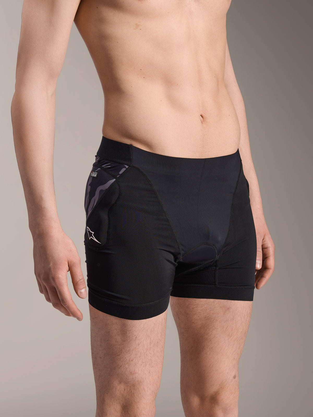 Alpinestars A-Motion Plasma skyddsboxershorts, svarta underställsshorts för cykling, kamouflagemönstrat höftskydd med vit Astar-logotyp, andningsbart meshtyg, skyddsutrustning för mountainbike
