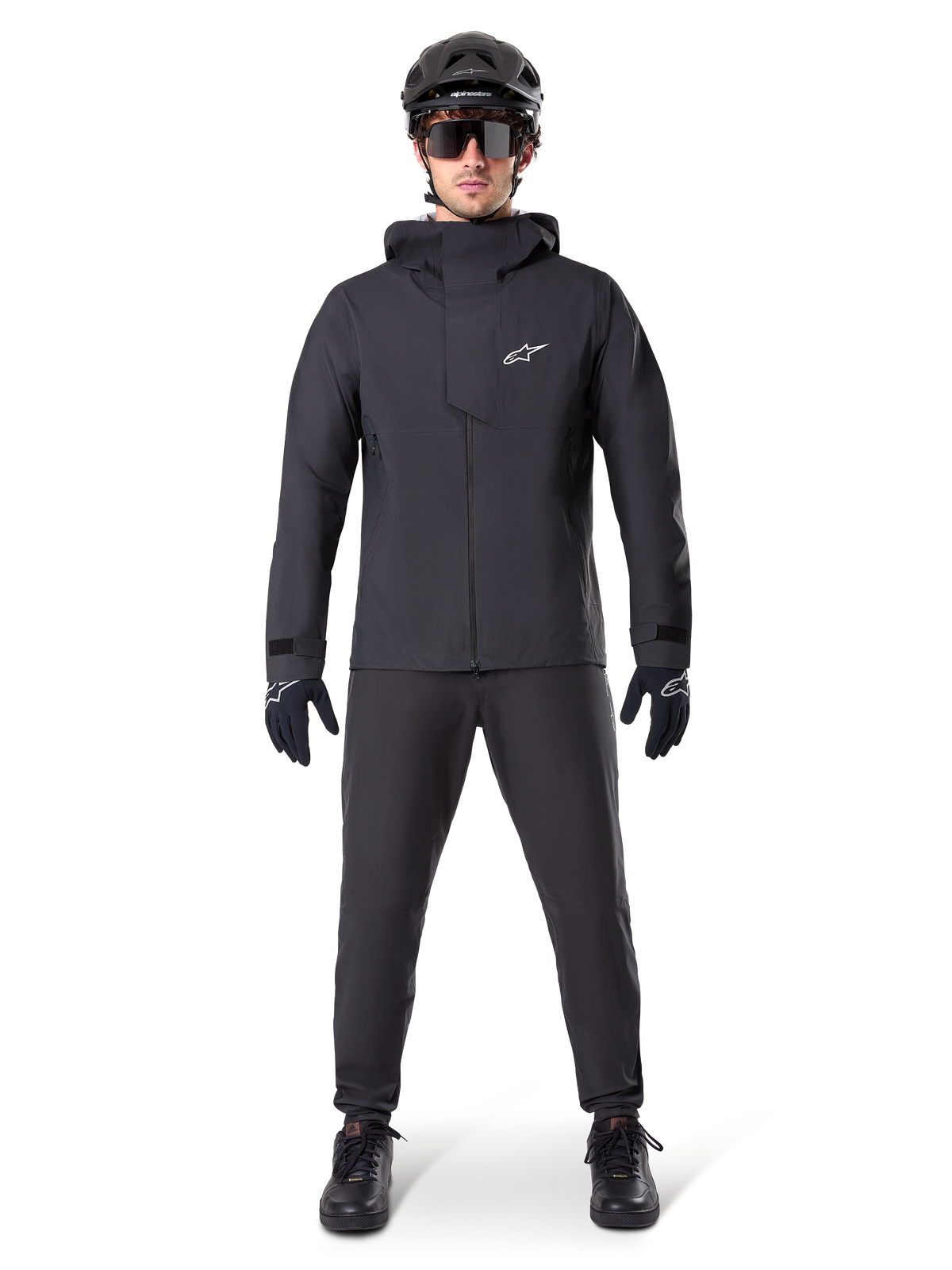 Alpinestars A-Dura Waterproof Pants, svarta MTB-byxor, bärs som en del av en komplett helsvart mountainbike-utrustning inklusive en teknisk vattentät jacka, svart hjälm, solglasögon och handskar, designade för terrängkörning i vått väder.