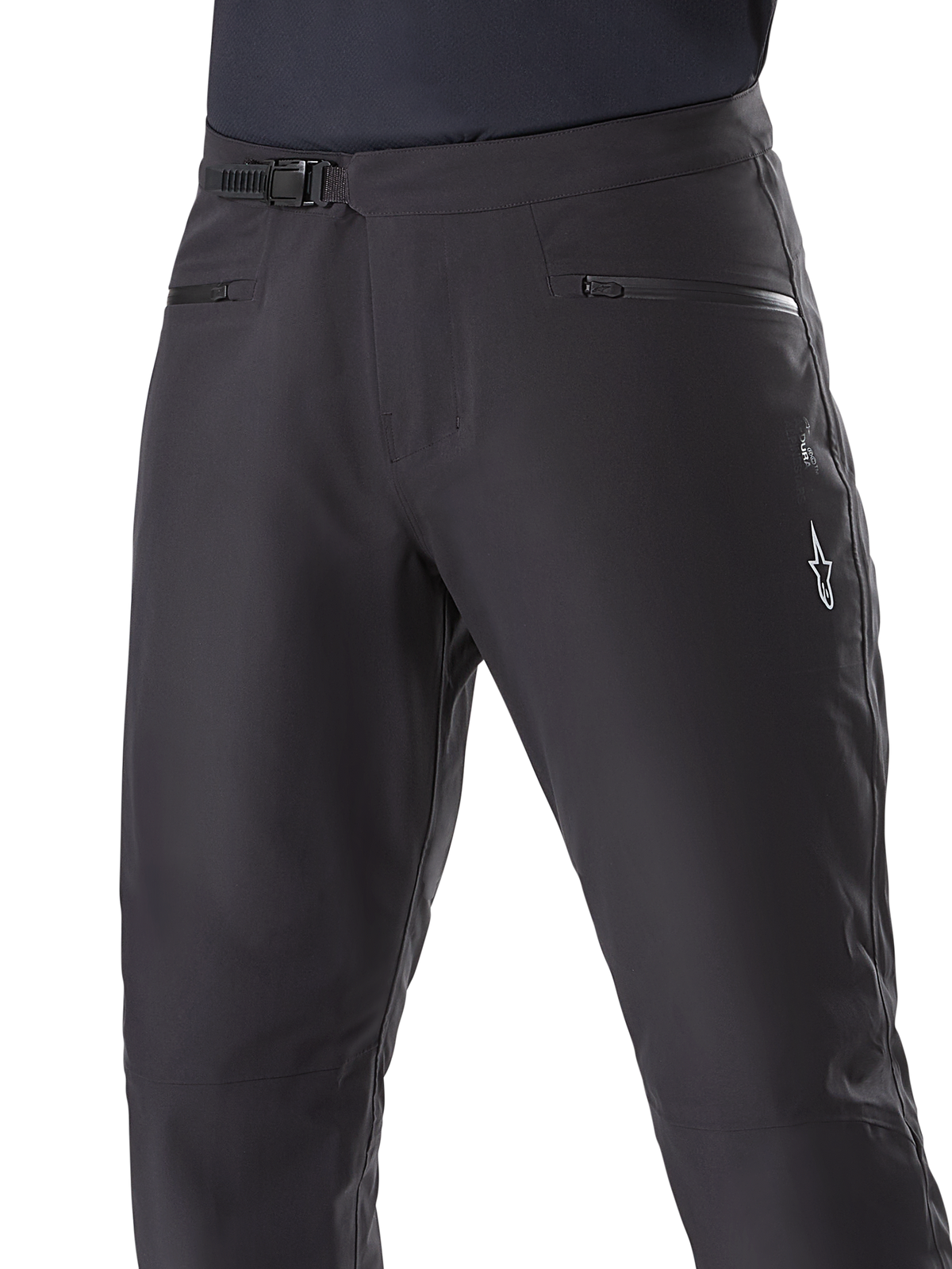 Alpinestars A-Dura Waterproof Pants, mountainbike-byxor, svarta, närbild av midjan som visar spärrspänne och fickor med dragkedja, vit Alpinestars-logotyp på låret, slitstarkt textilmaterial för terrängcykling i vått väder