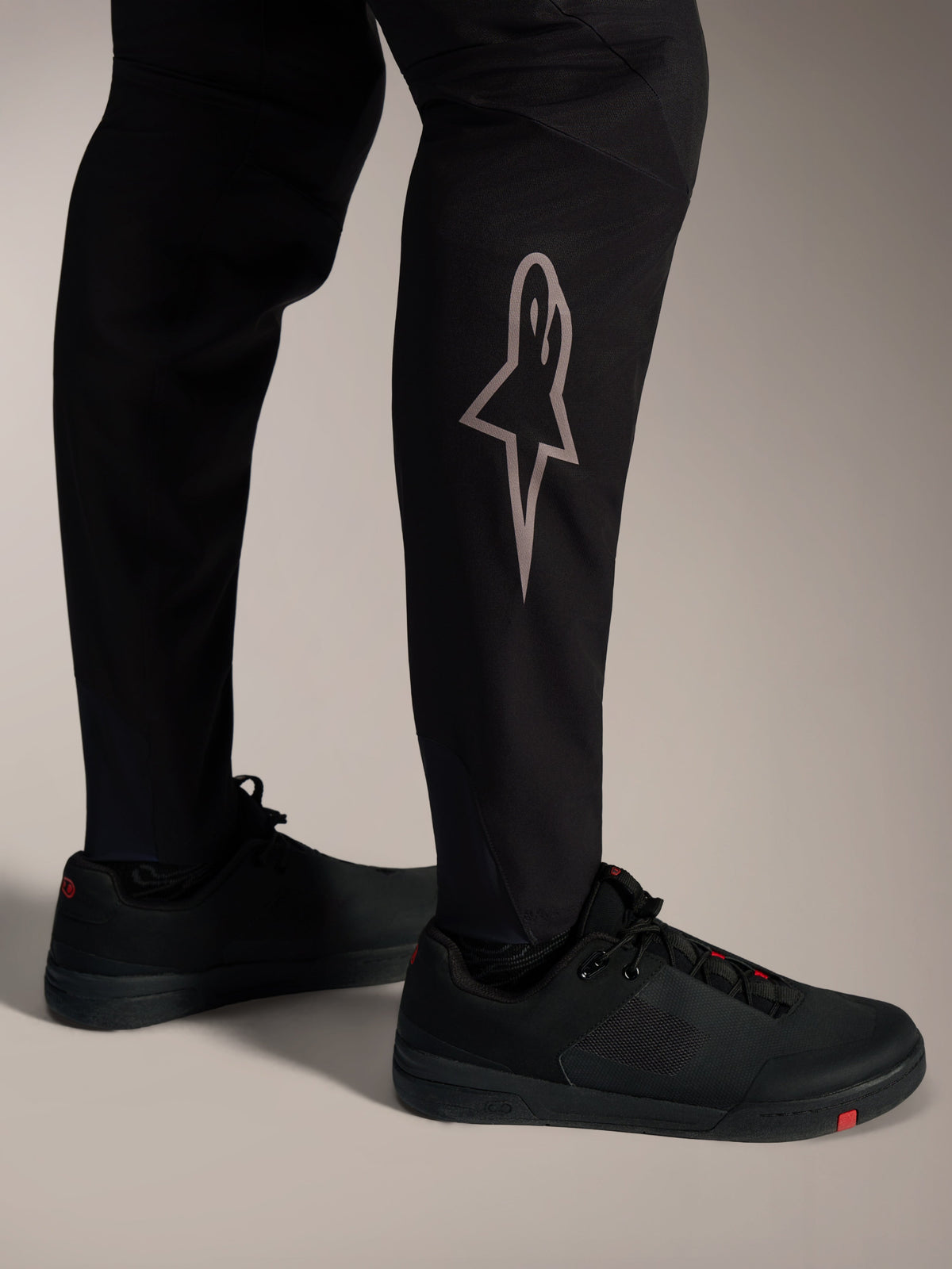 Svarta A-Supra Elite MTB-byxor med en silverfärgad Astars-logotyp på underbenet för högpresterande MTB-cykling.