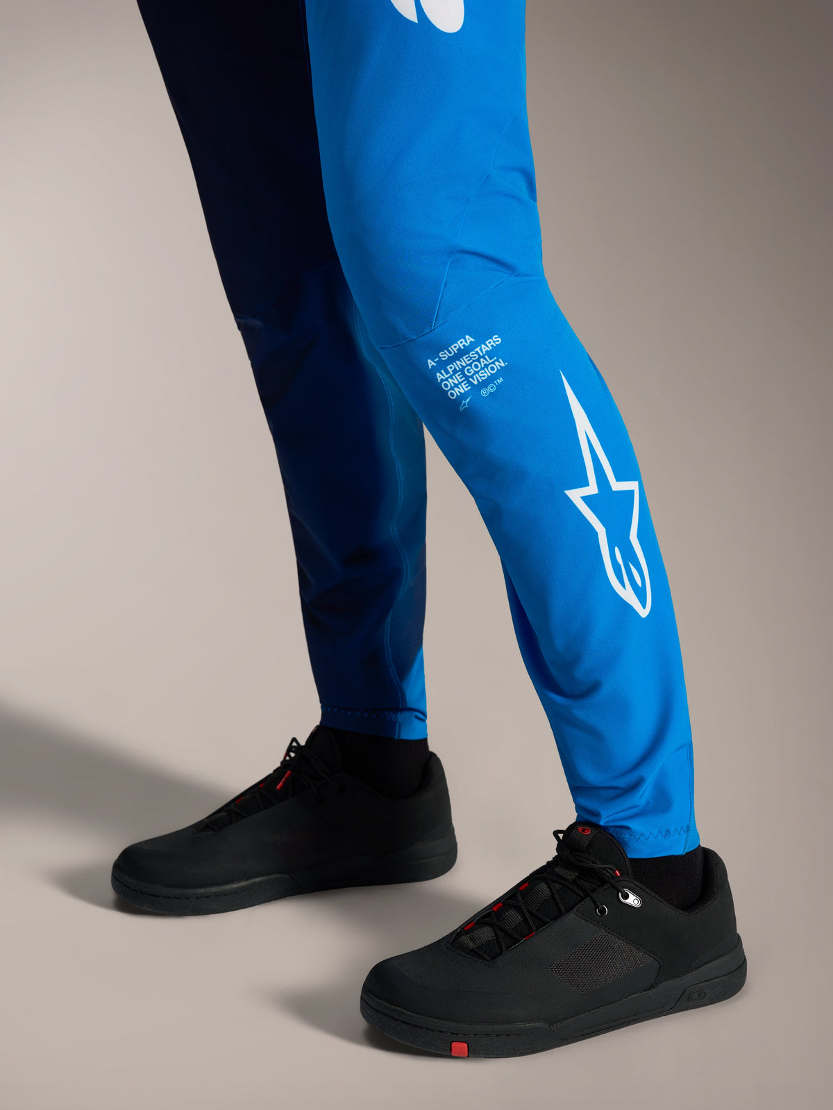A-Supra Elite-byxor i tonad klarblå med vit Astars-logotyp på benet, matchade med svarta MTB-skor.