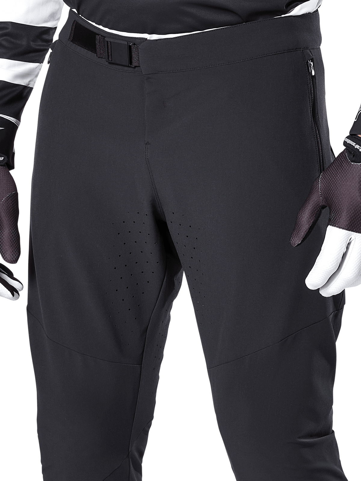 Alpinestars A-Aria Elite-byxor, svarta mountainbikebyxor, närbild på främre midja och lår med magnetspänne och laserskurna ventilationshål, tillsammans med cykelhandskar
