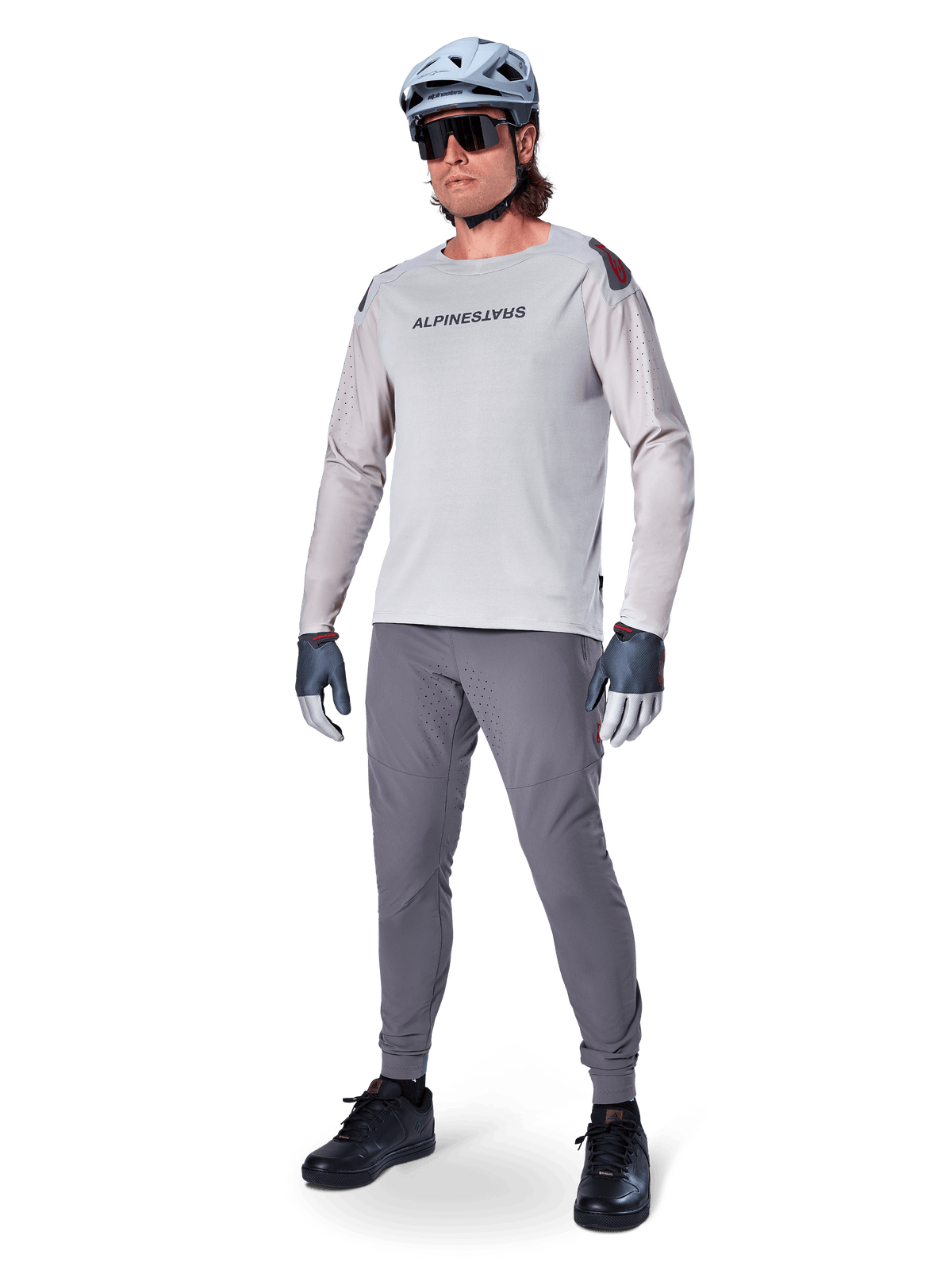 Alpinestars A-Aria Elite byxor, mörkgrå MTB-byxor, burna av en cyklist med en ljusgrå långärmad tröja och grå hjälm, med laserskuren ventilation på låren och en avsmalnande prestandapassform för mountainbikecykling.