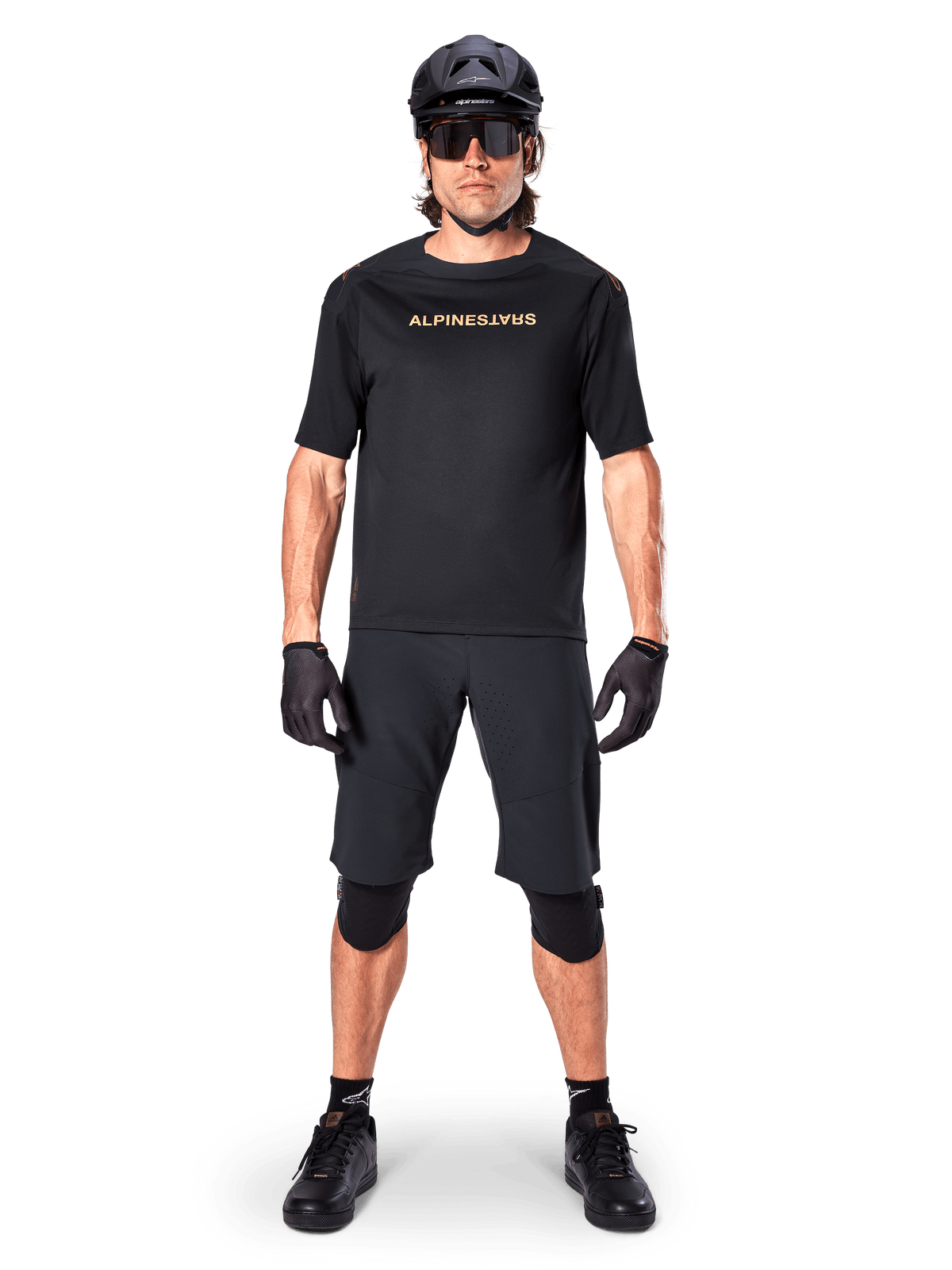 Manlig mountainbike-cyklist som bär Alpinestars A-Aria Elite Shorts i svart, kombinerat med en matchande svart kortärmad Alpinestars-tröja, svart hjälm, handskar och knäskydd, komplett outfit för terrängcykling