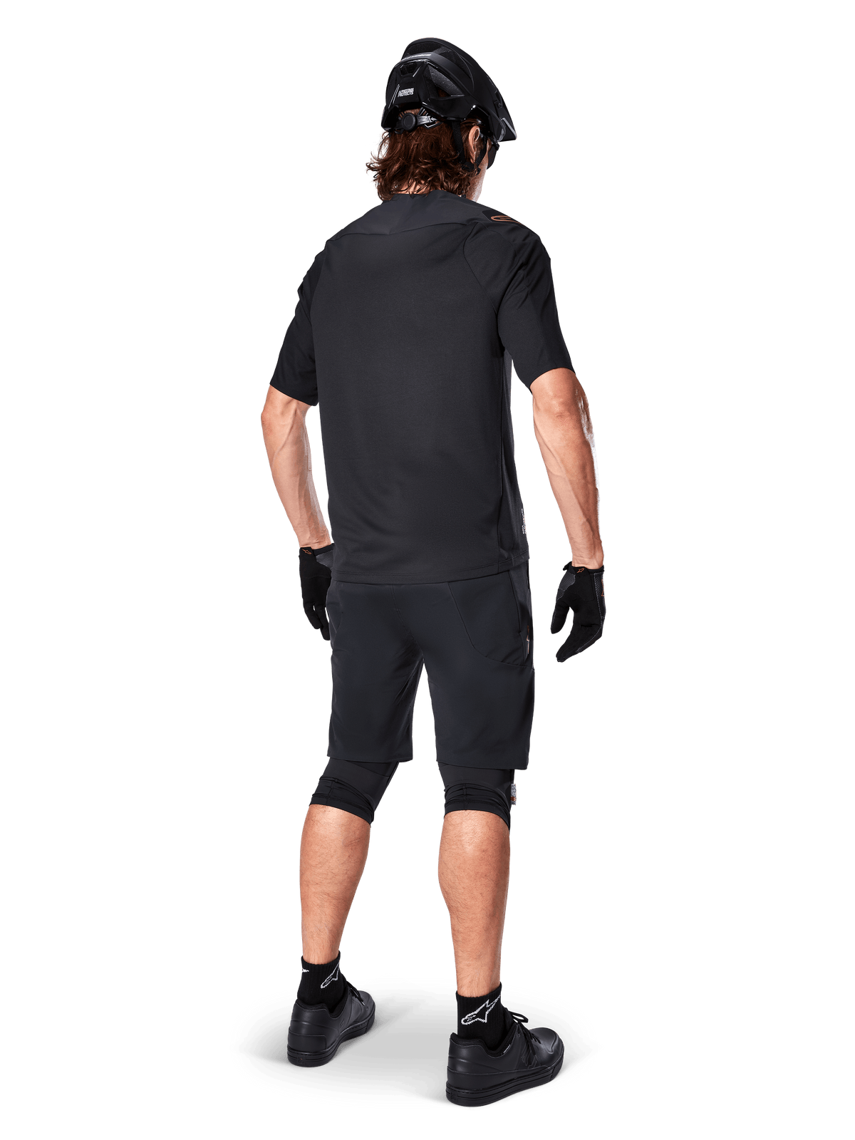 Vy bakifrån på en mountainbikecyklist som bär Alpinestars A-Aria Elite Shorts i svart, kombinerat med en matchande svart kortärmad tröja, svart hjälm, handskar och MTB-skor, vilket visar en komplett outfit för terrängcykling.