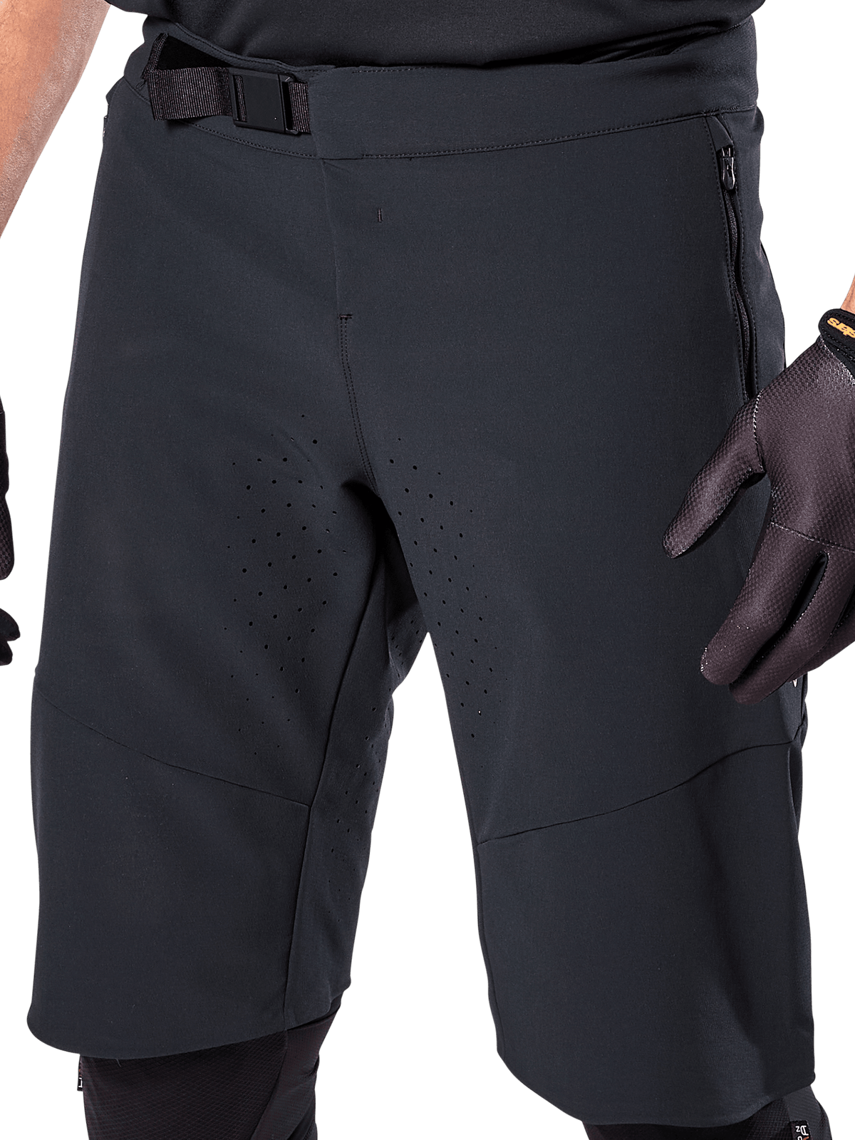 Alpinestars A-Aria Elite Shorts i svart, närbild på midje- och lårområdet, med magnetspänne, blixtlåsförsedda fickor och laserskurna ventilationsperforeringar, bärs med svarta cykelhandskar för mountainbike.