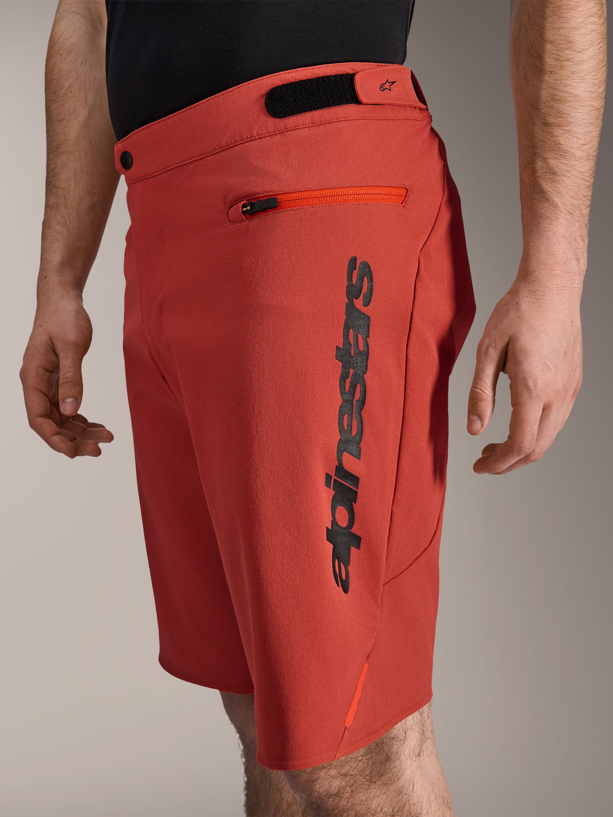 Alpinestars A-Dura Elite Shorts, mountainbikeshorts, mörkorange, med en vertikal svart Alpinestars-logotyp på sidan, ficka med dragkedja och kardborrejustering i midjan, slitstarka cykelkläder för terrängkörning