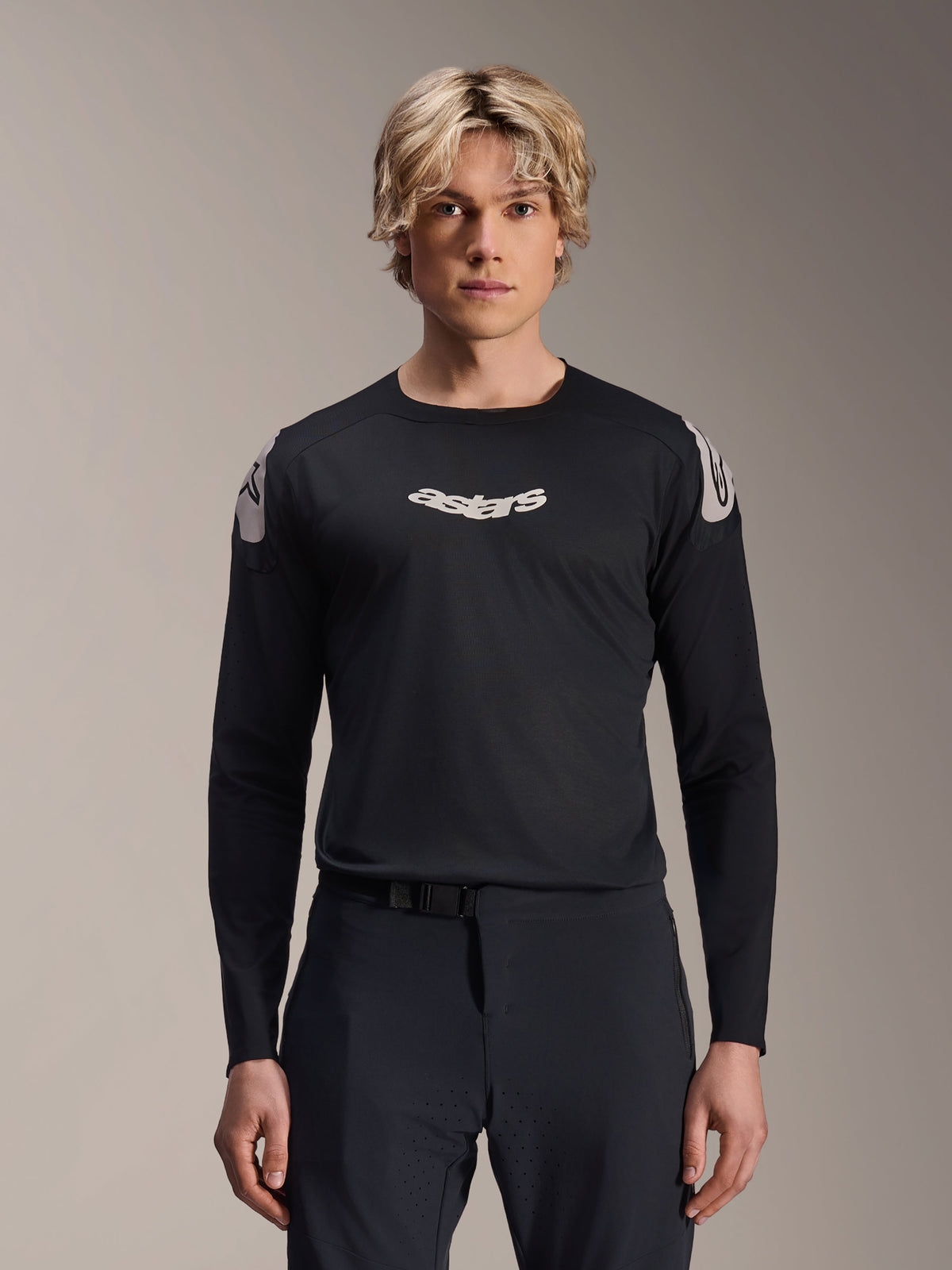 Alpinestars A-Aria Polartec Elite-tröja, långärmad MTB-tröja, svart, med vit ”astars”-logotyp på bröstet och vit axelgrafik, teknisk cykelutrustning buren av en modell