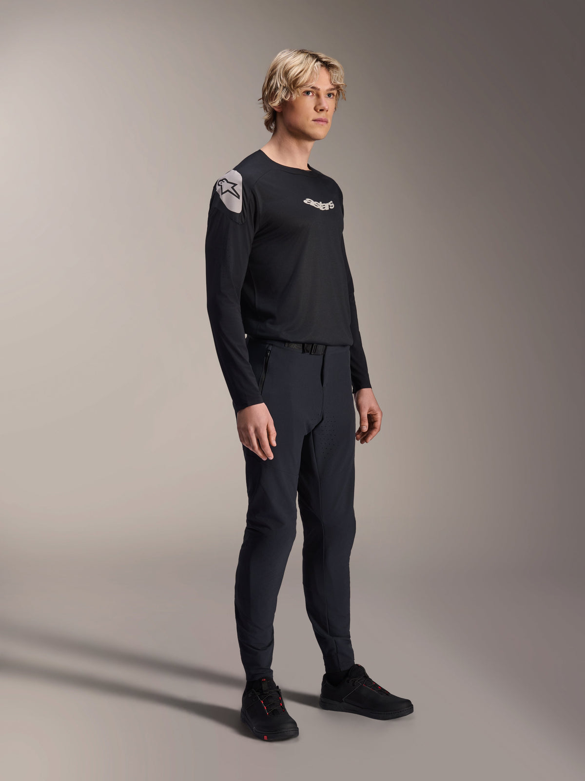 Modell iklädd Alpinestars A-Aria Polartec Elite långärmad tröja i svart, tillsammans med matchande svarta tekniska mountainbikebyxor och svarta skor, funktionella cykelkläder för terrängkörning, studiobild.