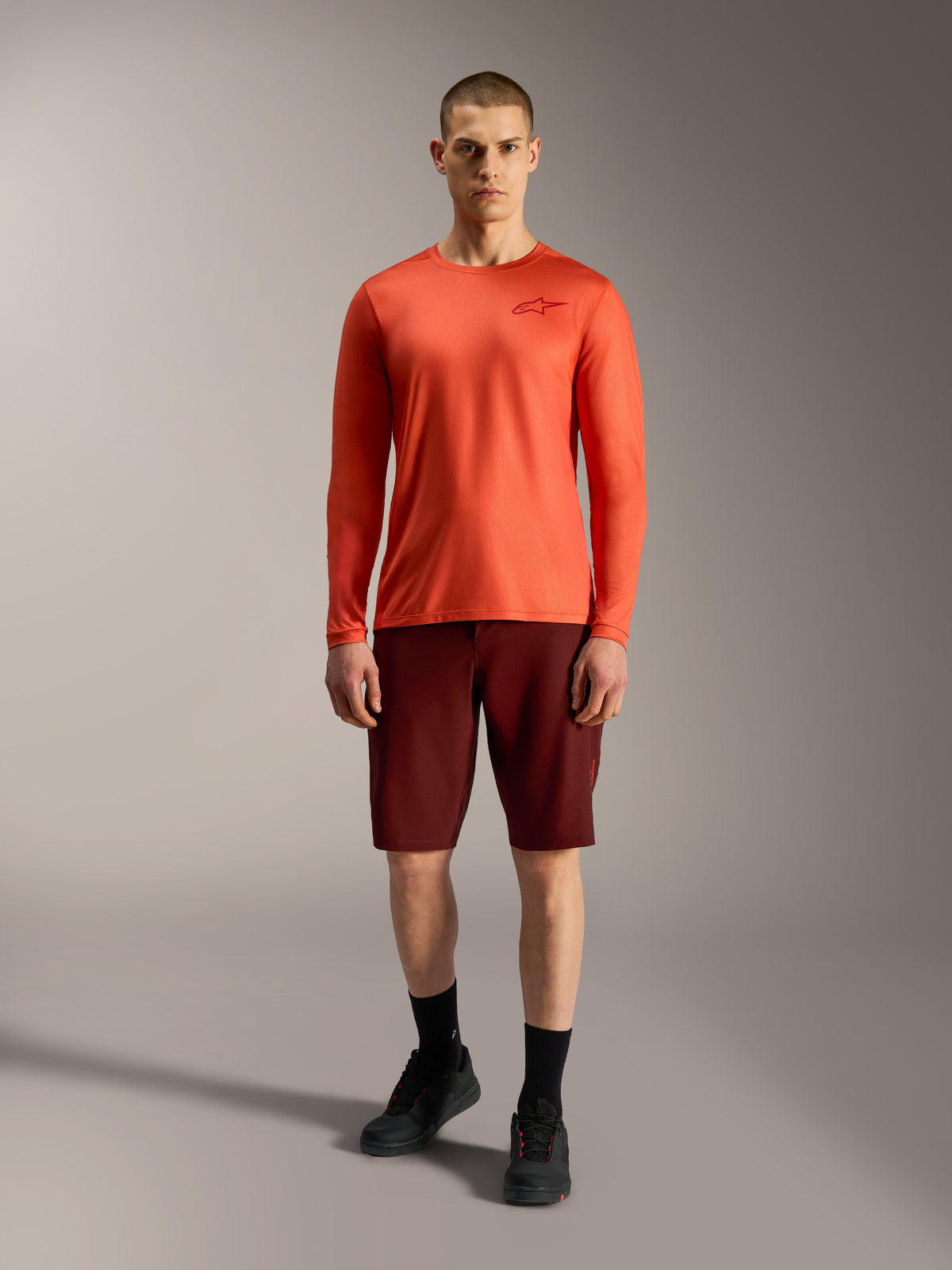 Alpinestars A-Dura Ride Shorts i Bordeaux och orange tröja, utvecklade för slitstark mountainbikeprestanda.