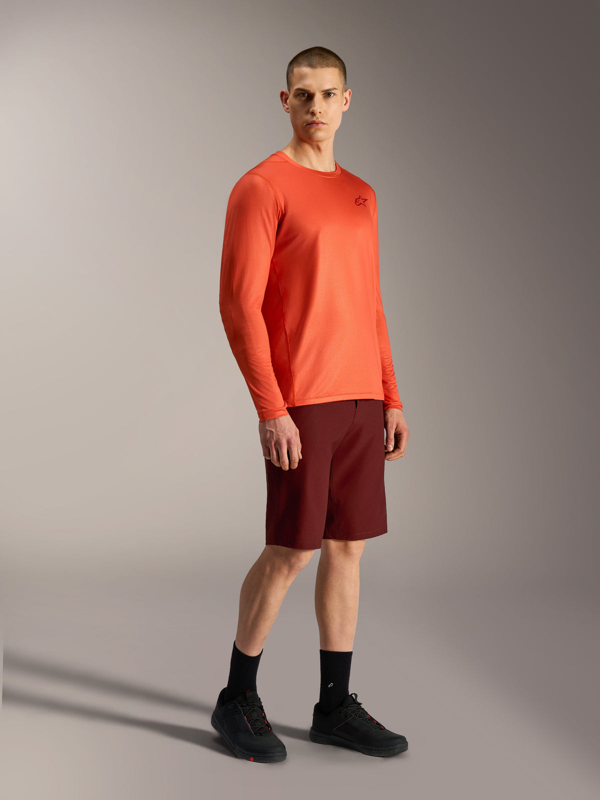 Alpinestars orange A-Dura Air långärmad tröja och bordeauxfärgade A-Dura Ride-shorts, professionell MTB-utrustning.
