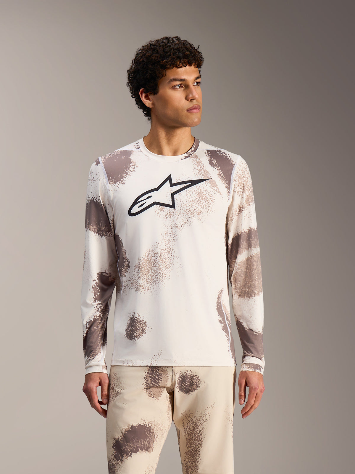 Alpinestars A-Dura Ride långärmad MTB-tröja i Sand Camo, vit design med abstrakta mönster och svart logotyp på bröstet.
