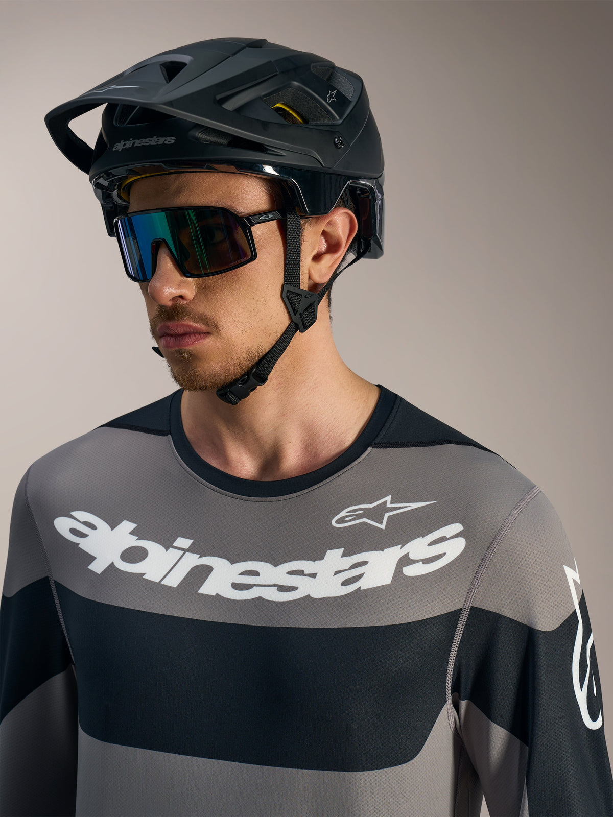 Alpinestars A-Dura Race långärmad tröja i grått med vita logotyper, svart MTB-hjälm och sportglasögon.