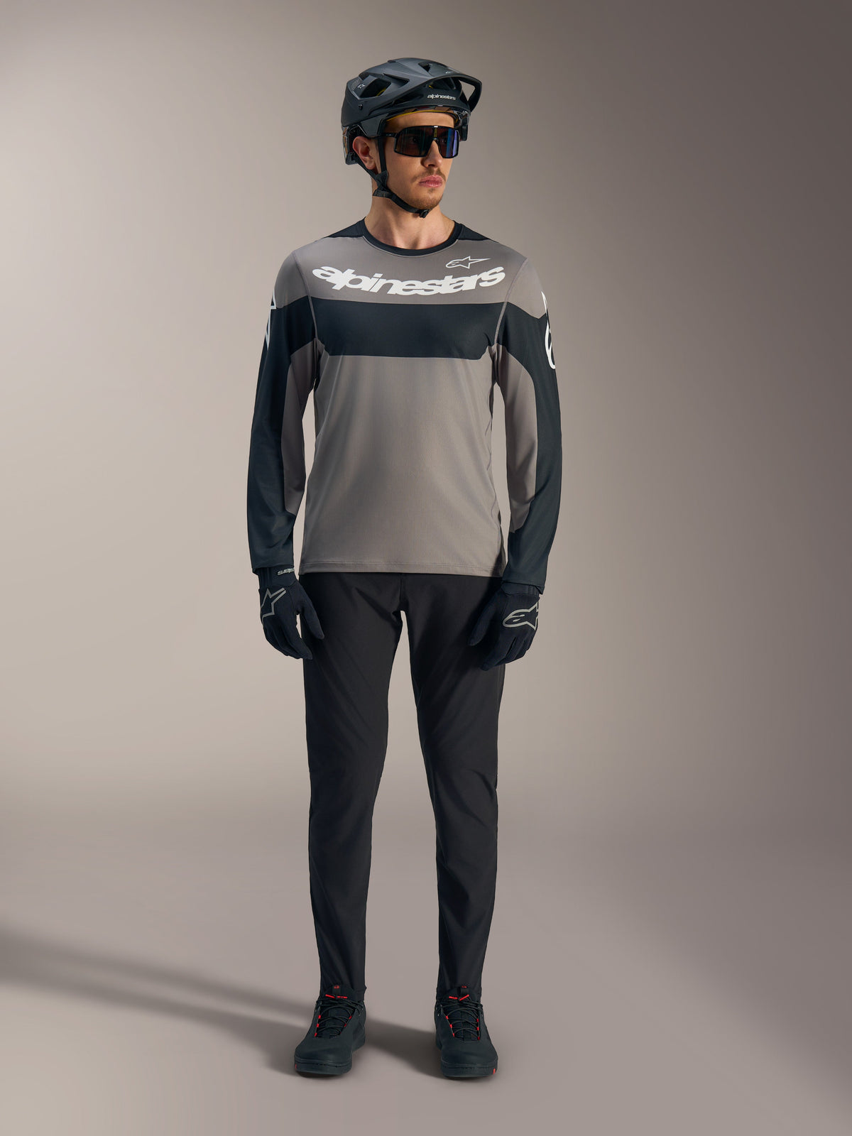A-Dura Race långärmad tröja i grått och svart med vit Alpinestars-logotyp, matchad med MTB-utrustning.