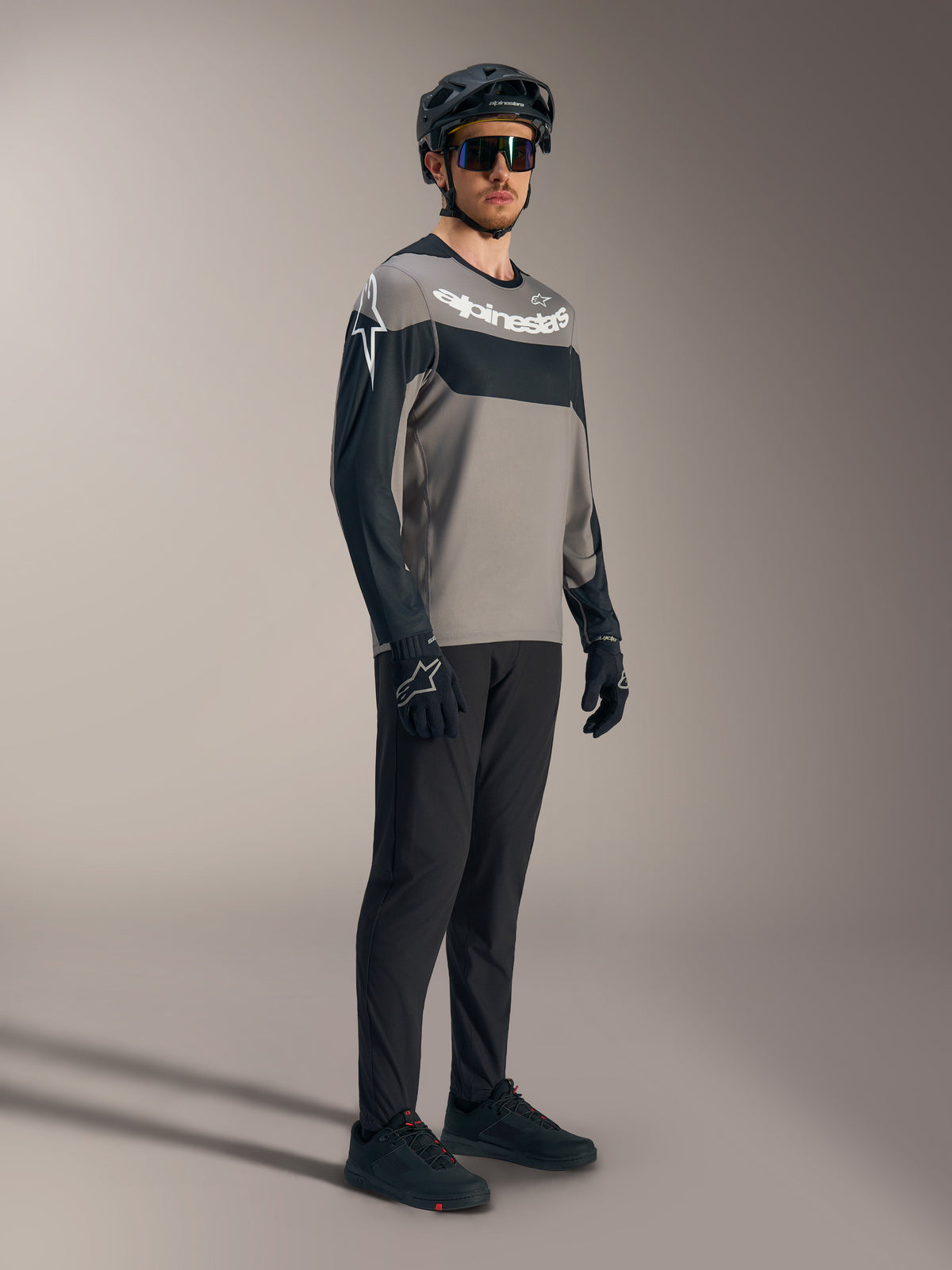 Alpinestars A-Dura Race långärmad tröja i grått och svart med vita logotyper, matchad med tekniska MTB-byxor och hjälm.