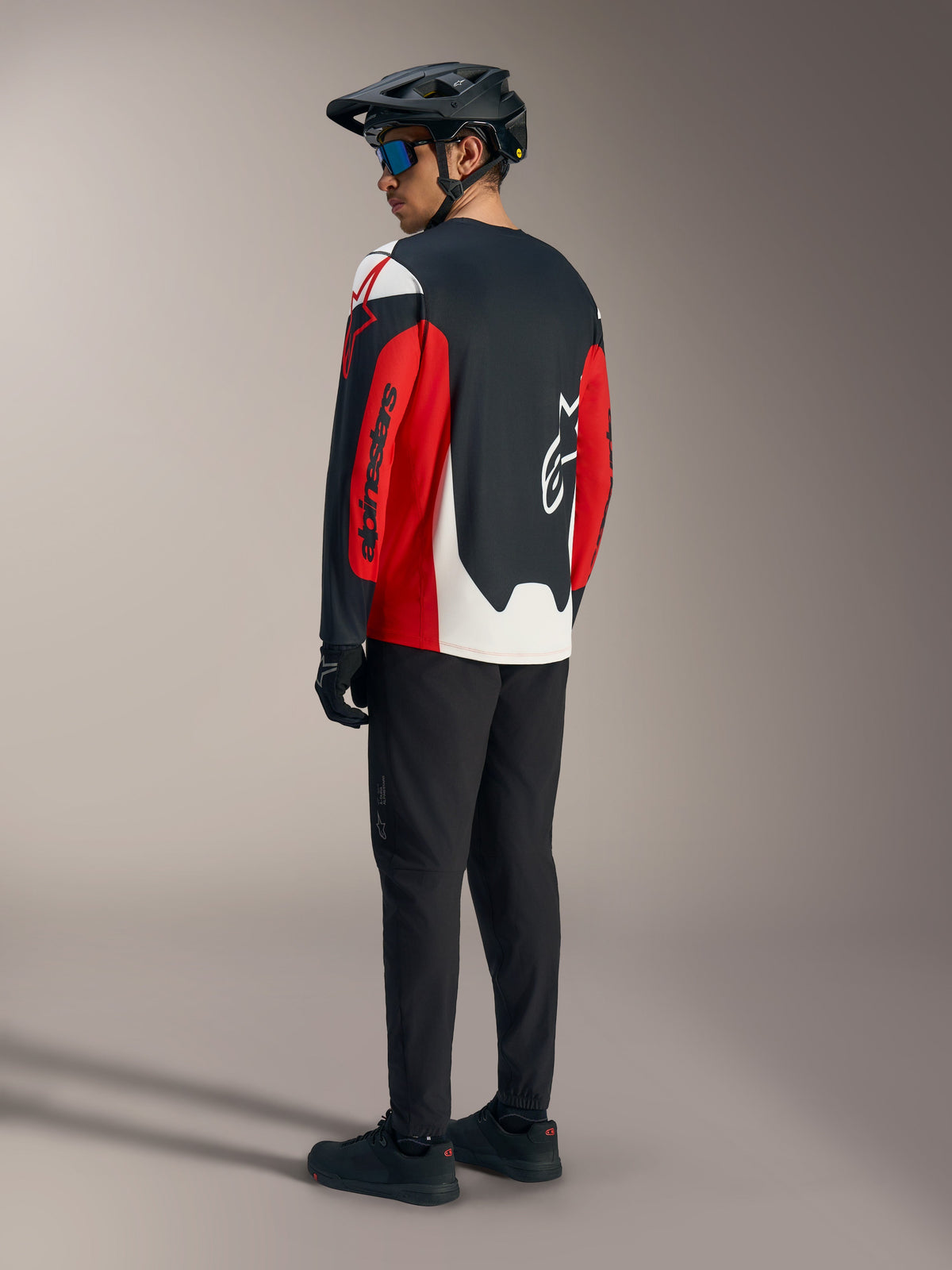 Röd Alpinestars A-Dura Race långärmad tröja med grafik, sedd bakifrån som del av en mountainbike-utrustning.