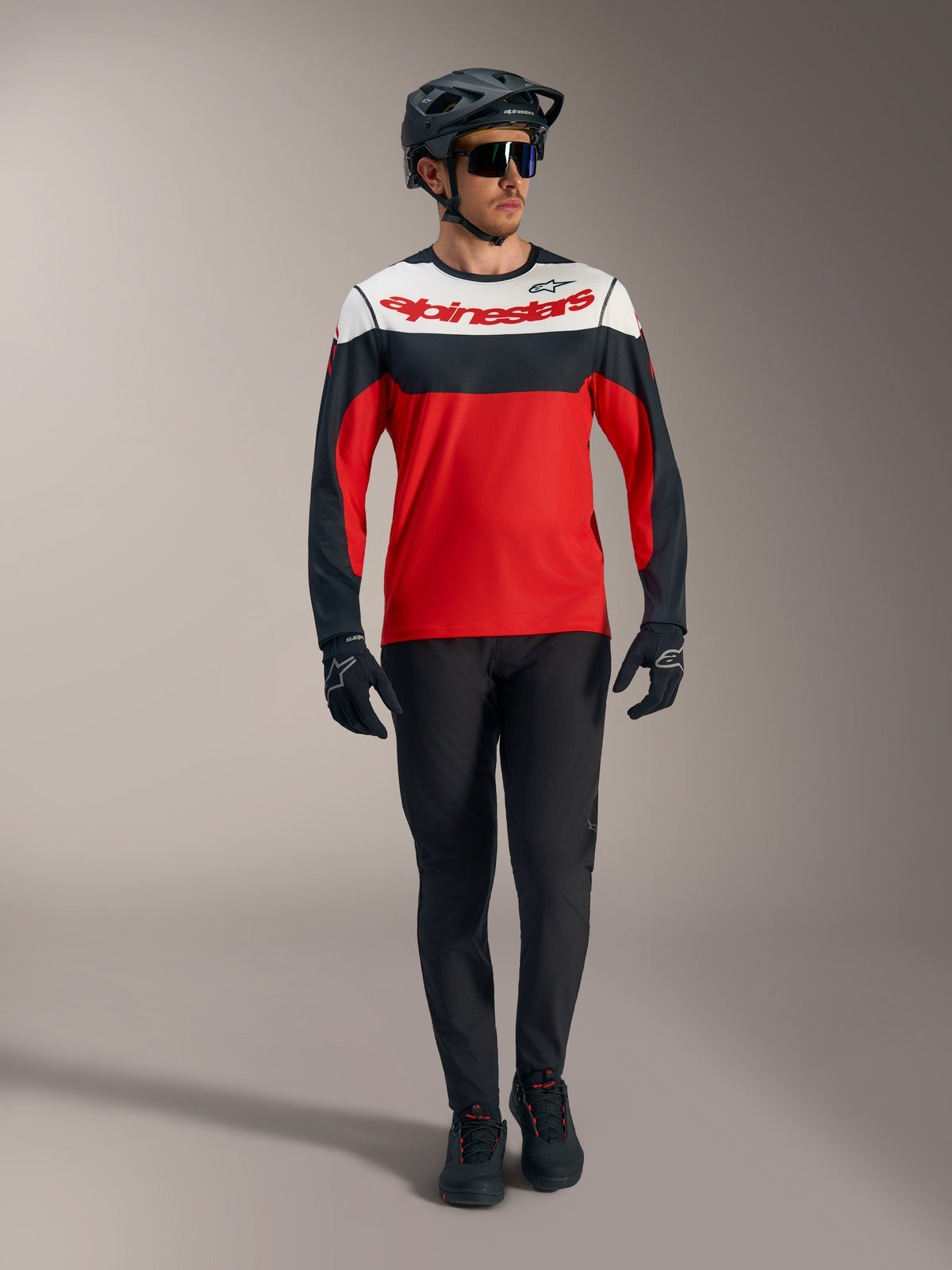 Alpinestars A-Dura Race långärmad tröja, röd med vita och svarta paneler, matchad med svarta MTB-byxor och hjälm.