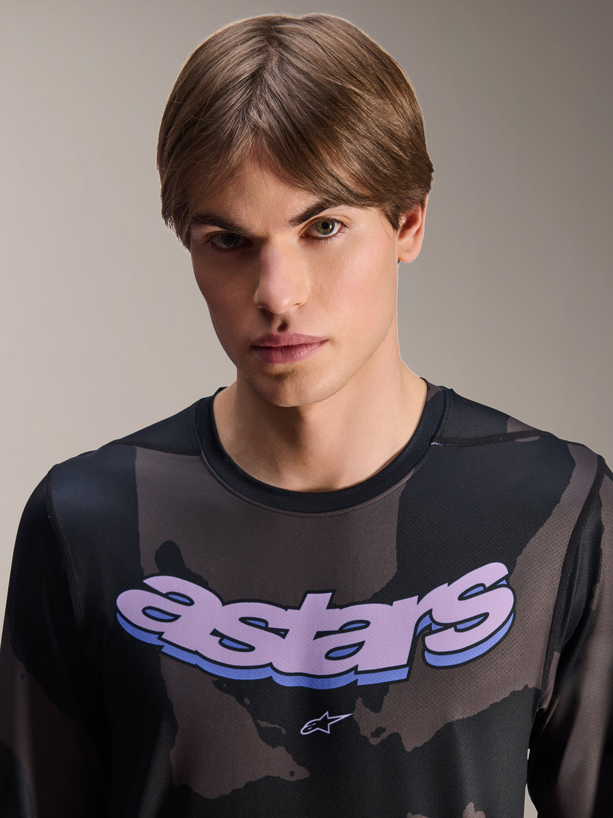 Alpinestars A-Dura Hollow Camo-tröja – långärmad, svart kamouflage med lila 'astars'-grafik på bröstet, studiobild på manlig modell i MTB-kläder, avslappnad och teknisk mountainbikestil