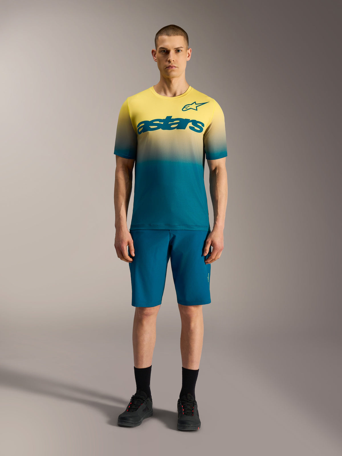 A-Dura ASTARS 2.0 Jersey, kortärmad MTB-tröja med gul och blå gradient och en tydlig Alpinestars-logotyp på bröstet.