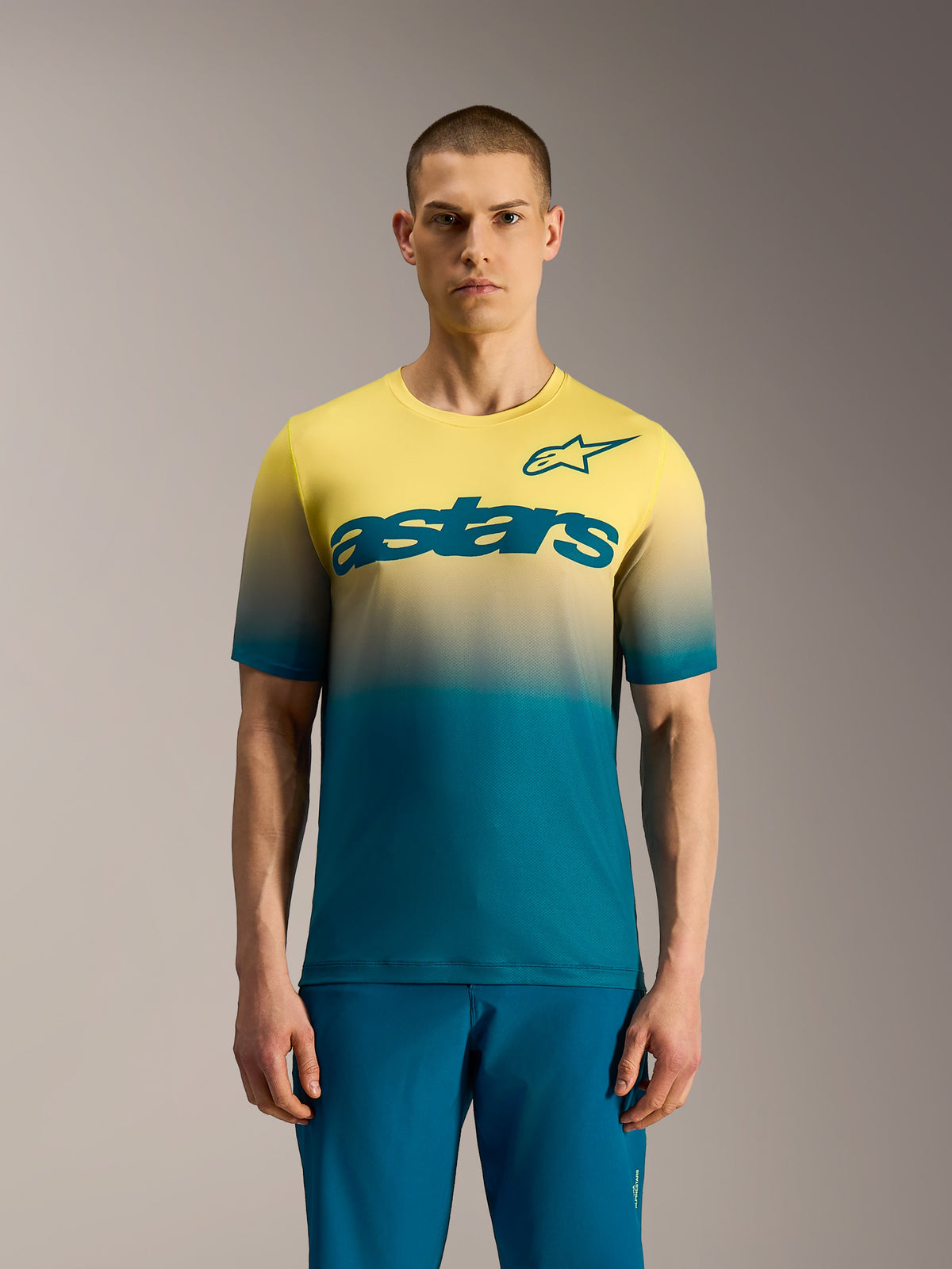 Alpinestars A-Dura ASTARS Jersey 2.0, kortärmad MTB-tröja med blågrön till neongul gradient och stor bröstlogotyp.