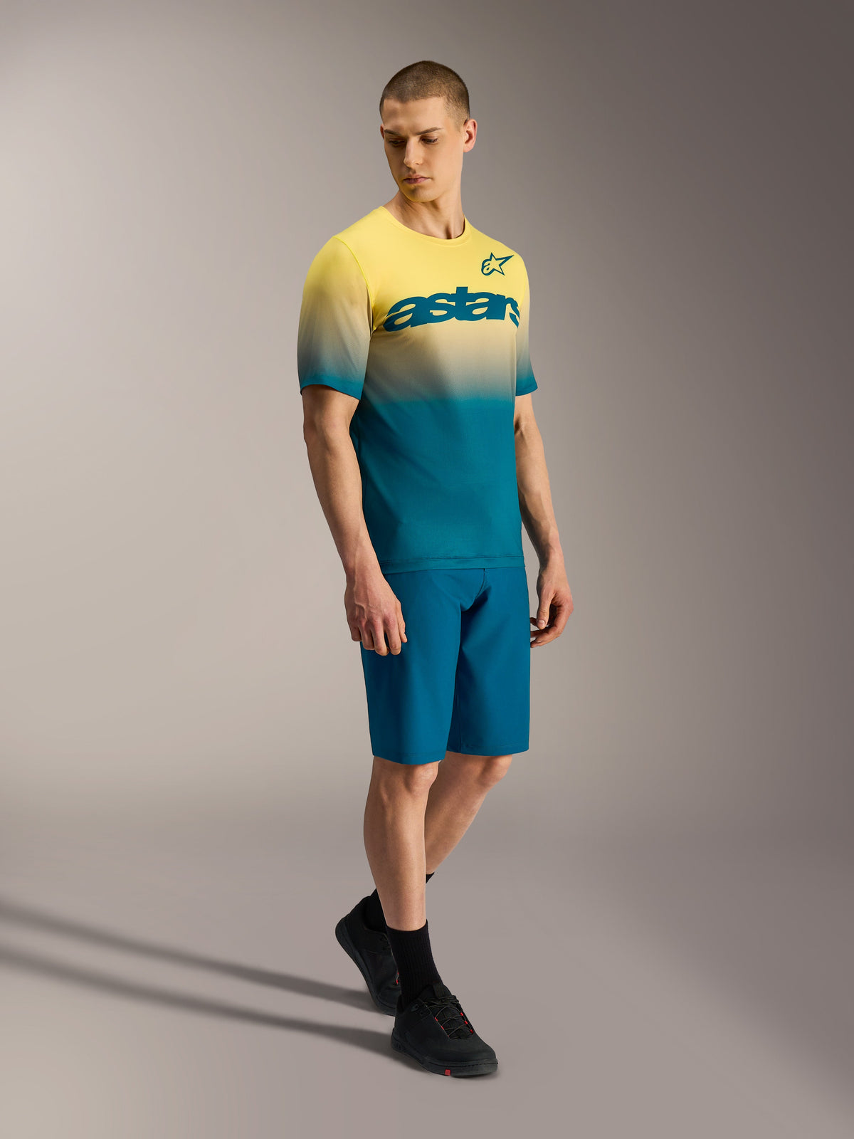 Alpinestars A-Dura ASTARS Jersey 2.0, kortärmad MTB-tröja med gul-blå toning och logotyp på bröstet på en modell.