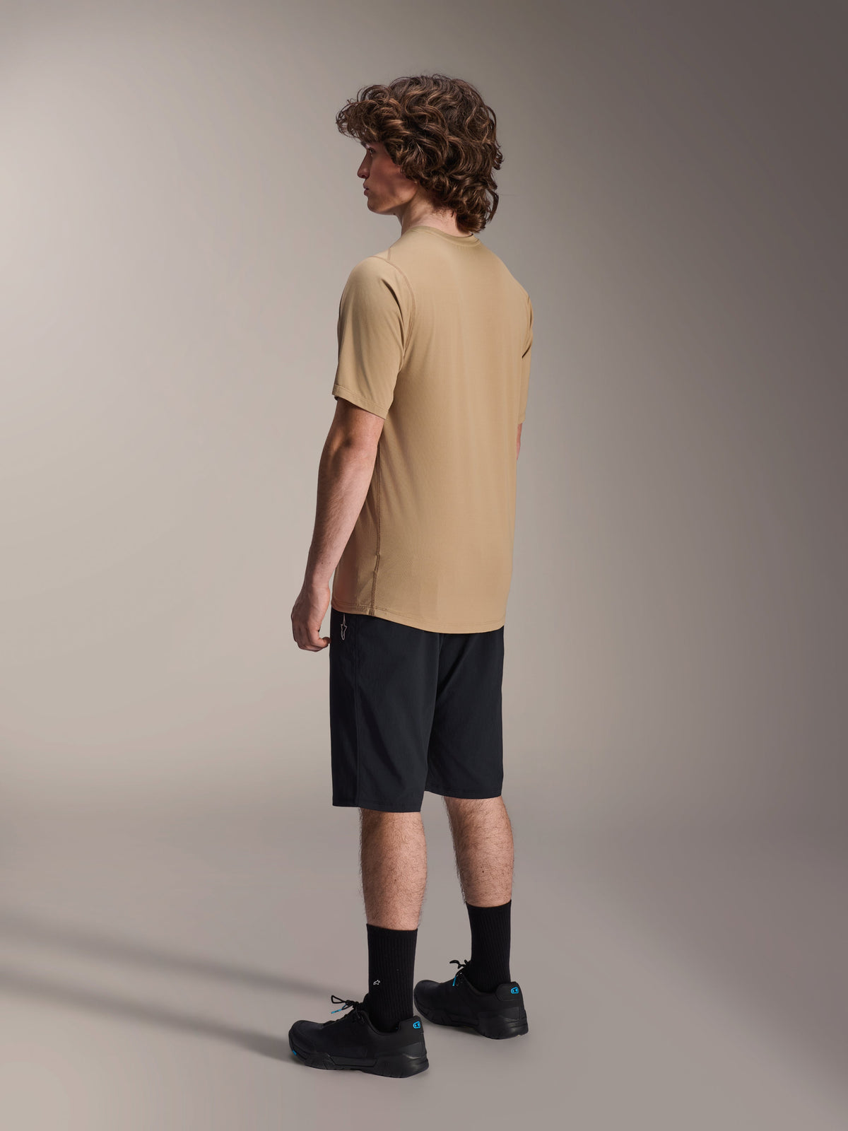 Alpinestars A-Dura Astar kortärmad tröja, ljusbrun, bärs med svarta shorts och svarta strumpor, fukttransporterande jacquard-tyg, avslappnade funktionskläder för mountainbike