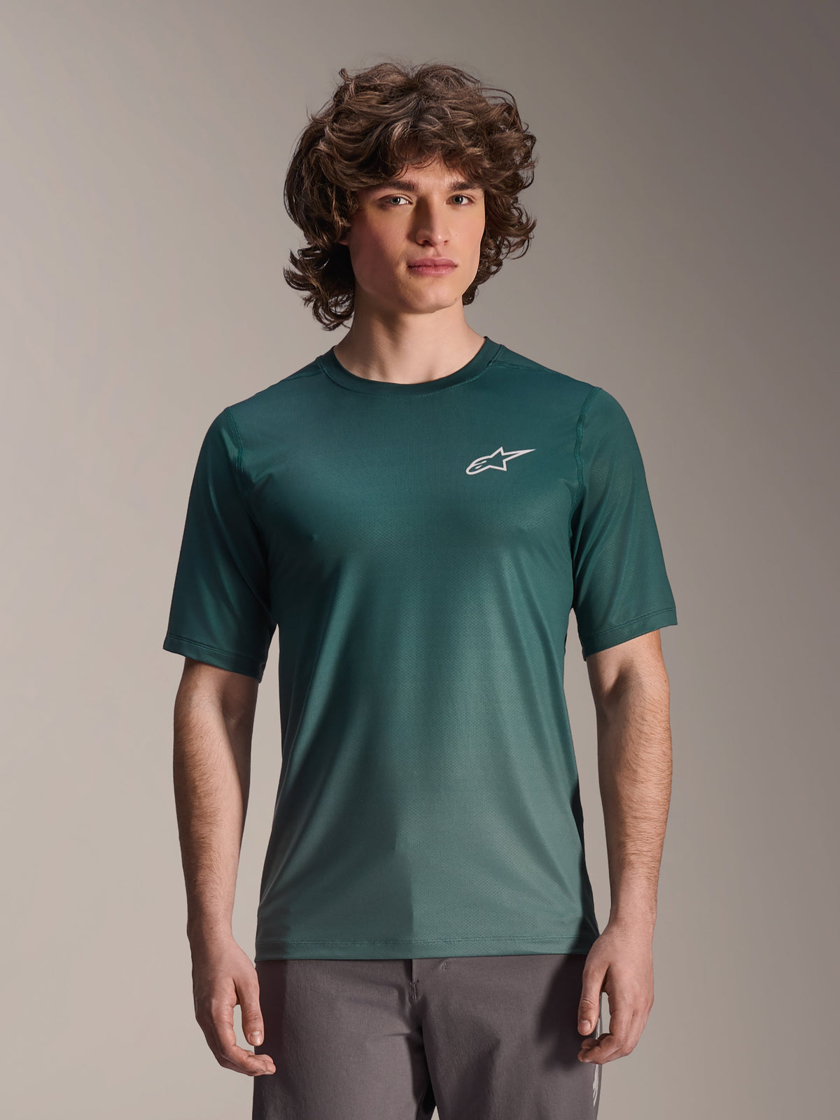 Alpinestars A-Dura Rise-tröja, kortärmad, mörkgrön Silver Pine, bärs av en modell, vit Astars-logotyp på bröstet, lätt fukttransporterande jacquard-material, avslappnad funktionströja för mountainbike