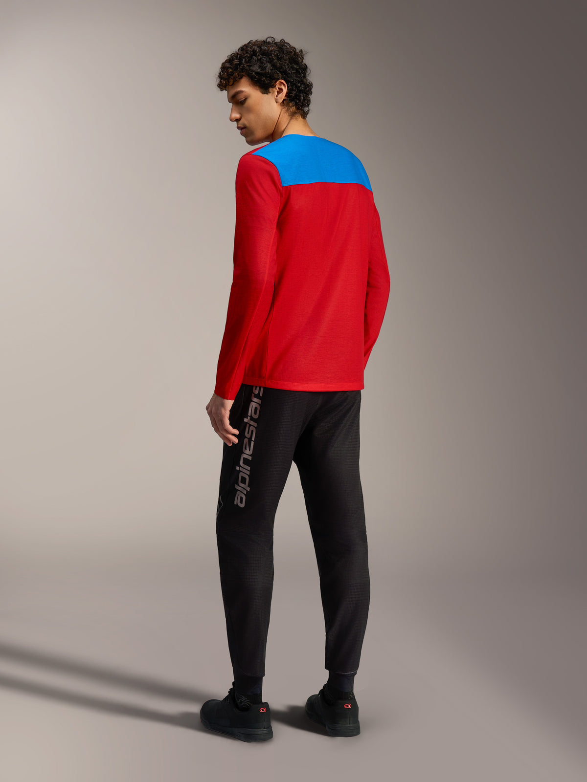 Alpinestars A-Dura Elite Jersey 2.0 in red with blue back panel, long sleeve MTB top worn with black performance pants.