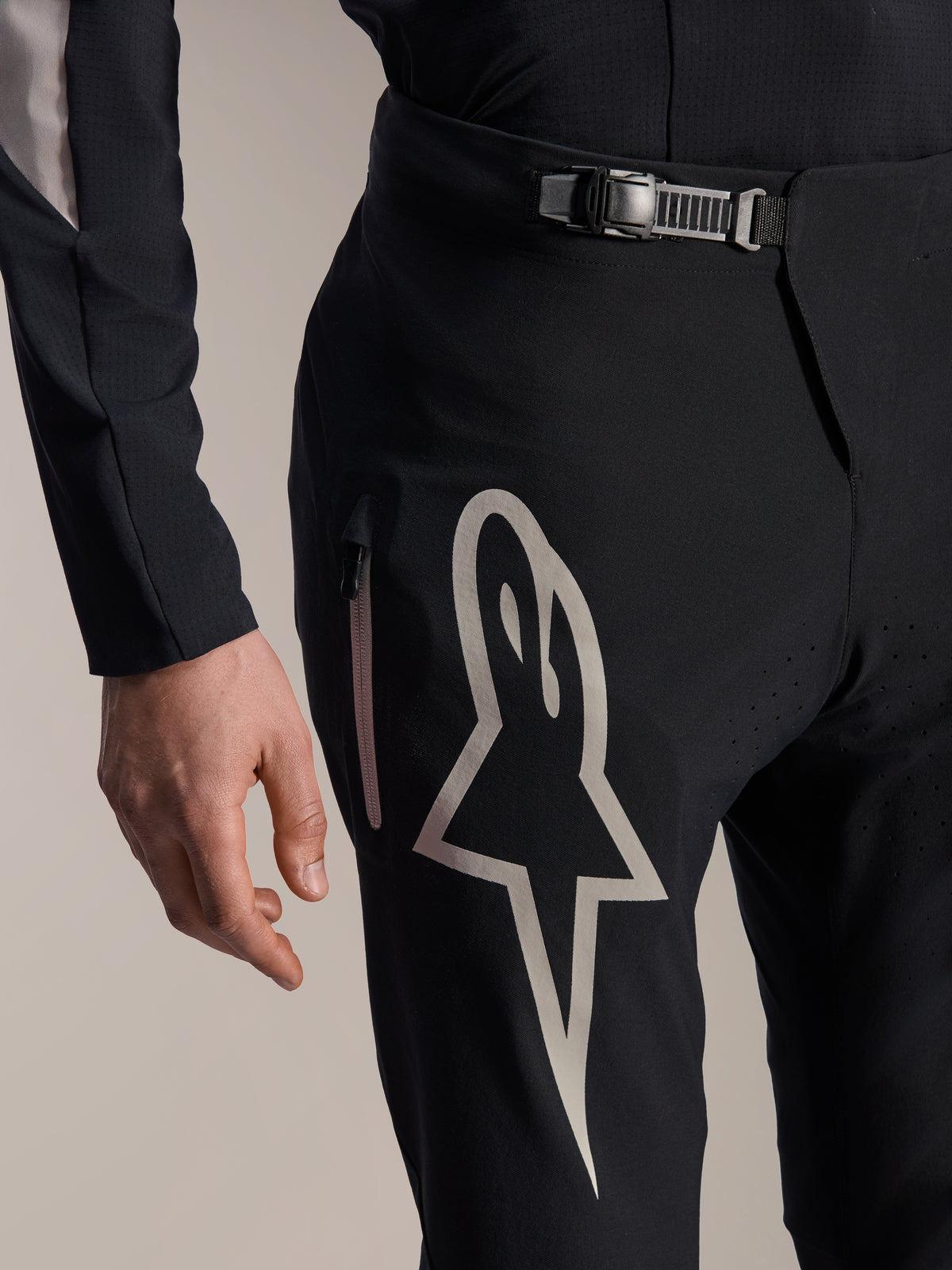 Alpinestars A-Supra Melt-byxor, mountainbike-byxor, svarta med en stor vit Astars-logotyp på låret, justerbar ratchet-stängning i midjan och sidoficka med dragkedja, detaljerad vy av teknisk MTB-utrustning