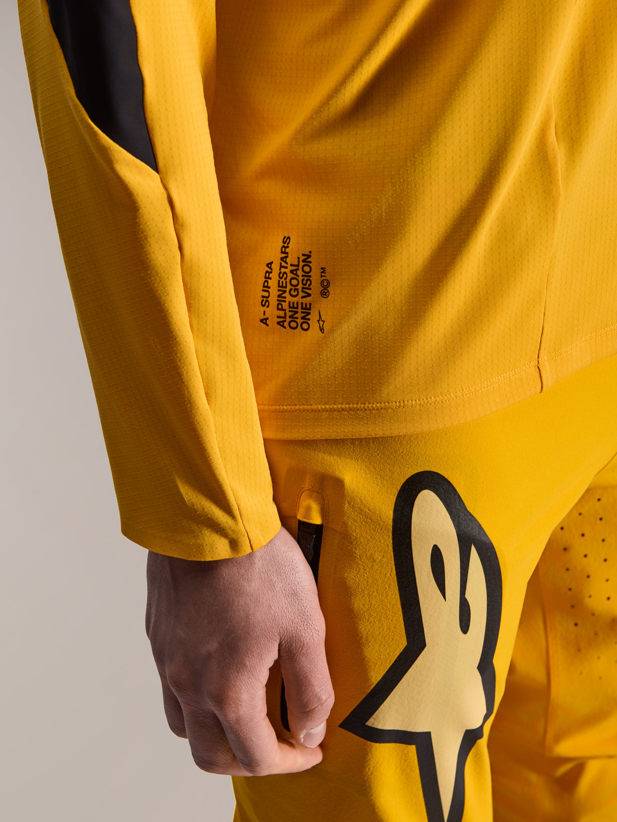 Alpinestars Limited Edition A-Supra Melt Gold-byxor och matchande långärmad tröja, mörkgul, närbild med 'One Goal. One Vision.'-branding och stor stiliserad logotyp på låret, högpresterande MTB-utrustning