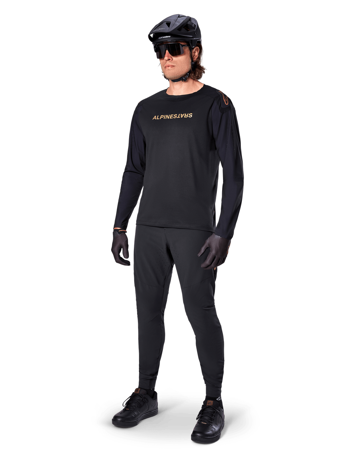 Alpinestars A-Aria Polartec Switch långärmad tröja, svart, bronsfärgad logotyp på bröstet, bärs av mountainbikecyklist med svart hjälm och solglasögon, prestandakläder för stigcykling