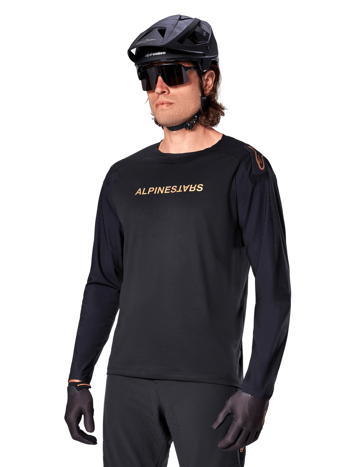 Alpinestars A-Aria Polartec Switch långärmad tröja, svart med guldlogotyp, MTB-kläder, bärs med en svart hjälm och solglasögon, med laserskuren ventilation på ärmarna och fukttransporterande Polartec-tyg för terrängprestanda