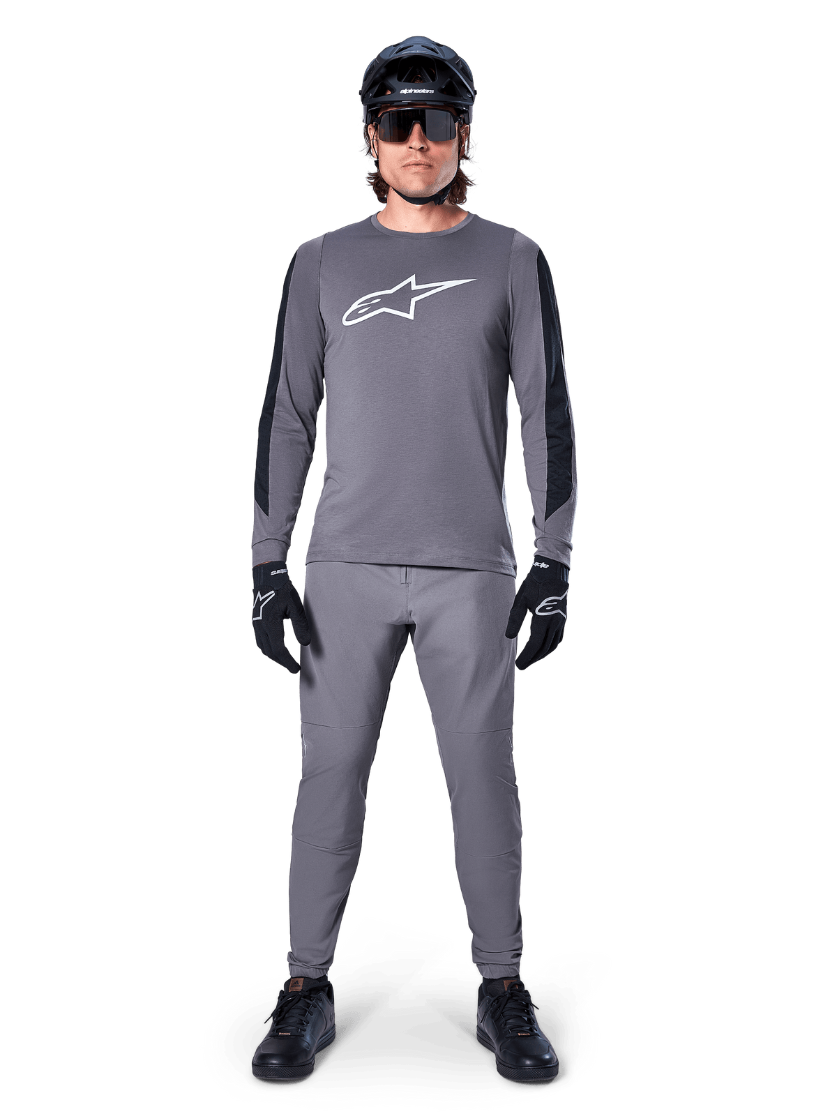 Alpinestars A-Dura Dri Astar-tröja, långärmad MTB-tröja i mörkgrått, med vit logotyp på bröstet och svarta paneler på ärmarna, bärs med matchande grå byxor, svart hjälm, solglasögon och handskar för en komplett outfit för terrängcykling
