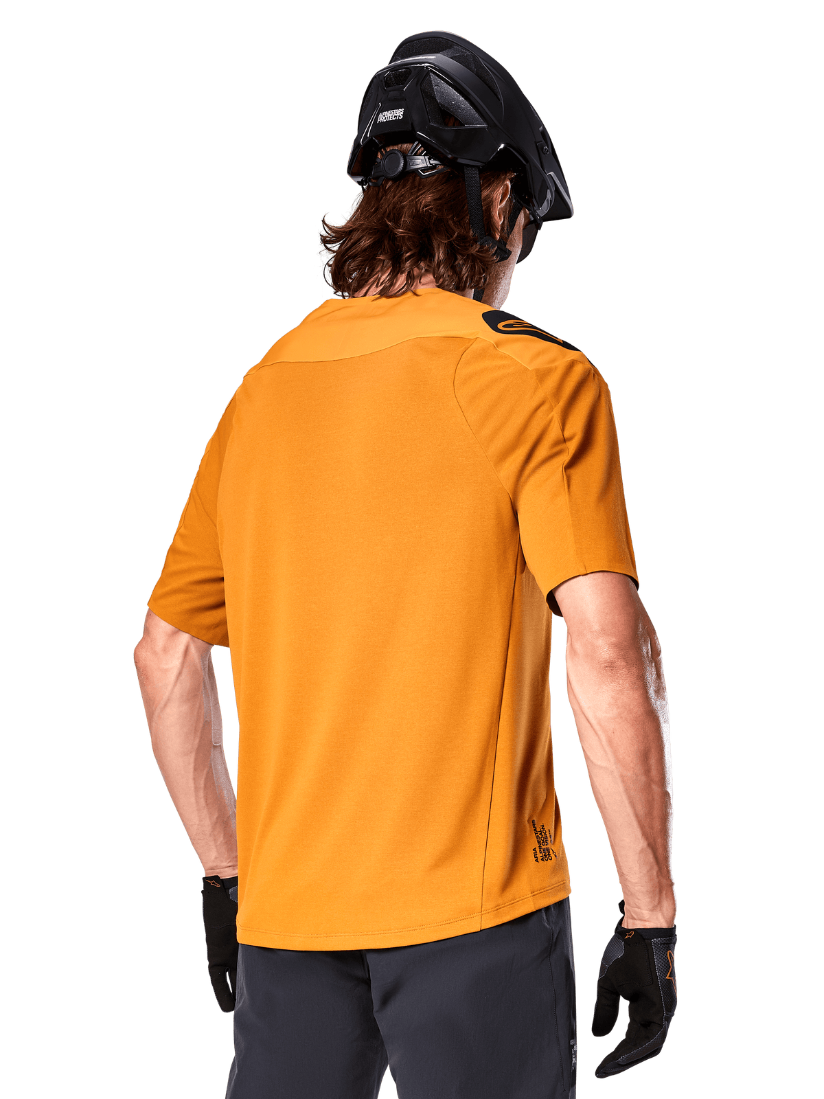 Alpinestars A-Aria Polartec Switch tröja, kortärmad MTB-tröja, Dark Gold, vy bakifrån som visar prestandapassform, bärs med svart hjälm och gråa shorts, slitstarka och ventilerande kläder för stigcykling