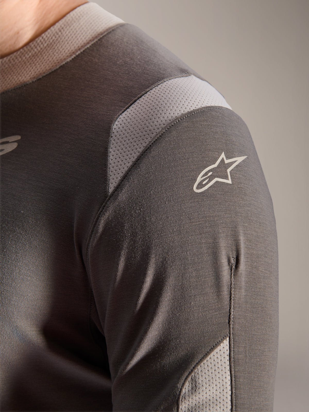 Alpinestars A-Dura Dri Wool Jersey - Long Sleeve, mörkgrå, detaljerad vy av axeln och ärmen som visar ljusgrå ventilationspaneler i mesh och den vita Astars-logotypen på det tekniska drirelease-tyget.