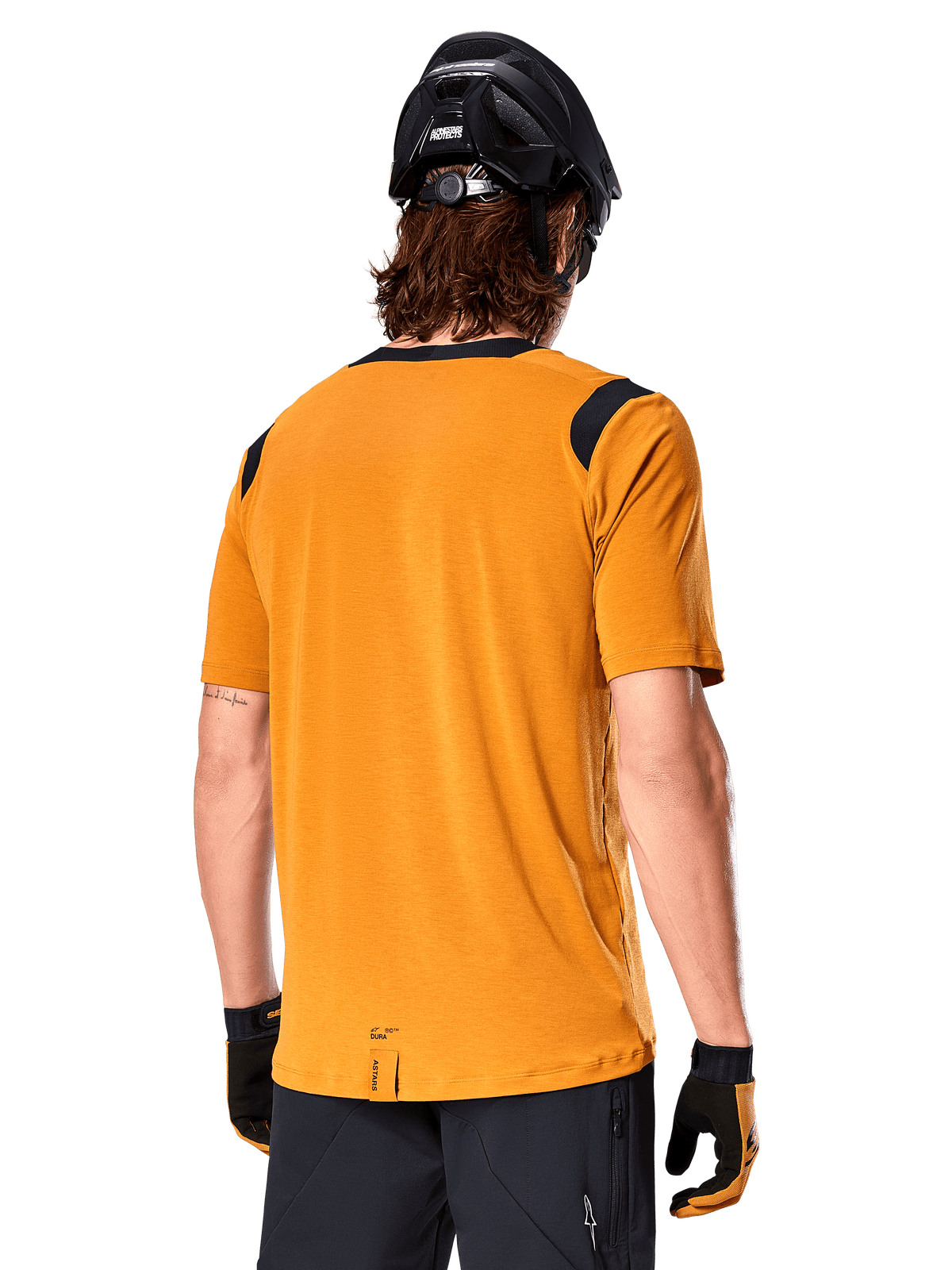 Alpinestars A-Dura Dri Wool kortärmad tröja, Dark Gold, ryggvy av en man som bär den kortärmade tröjan med svarta meshpaneler på axlarna, kombinerad med en svart MTB-hjälm och handskar, mountainbike-utrustning i normal passform.