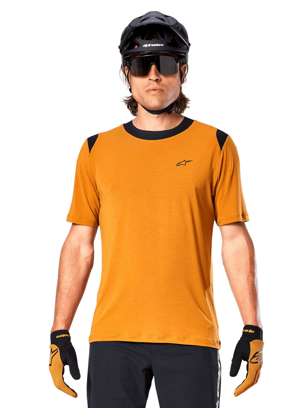 Alpinestars A-Dura Dri Wool kortärmad tröja, mörkguld, bärs med svart MTB-hjälm, solglasögon och handskar, med svart krage och axelpaneler, ventilerande drirelease-ullblandning för mountainbikecykling